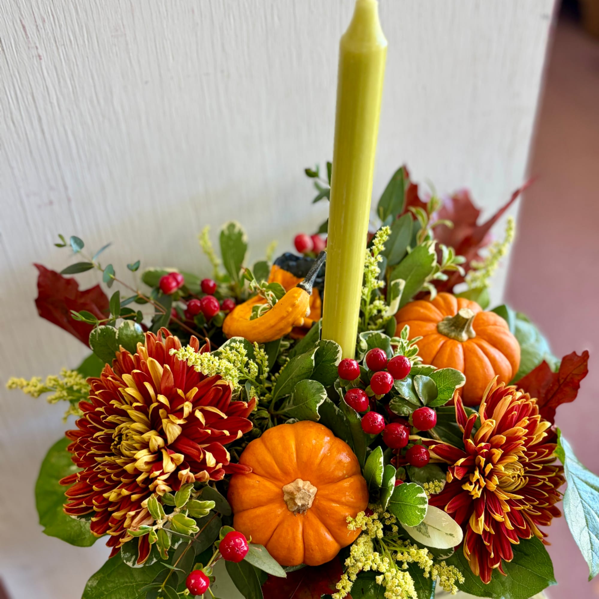 Autumn floral arrangement with chrysanthemums, mini pumpkins, and berries in a vase