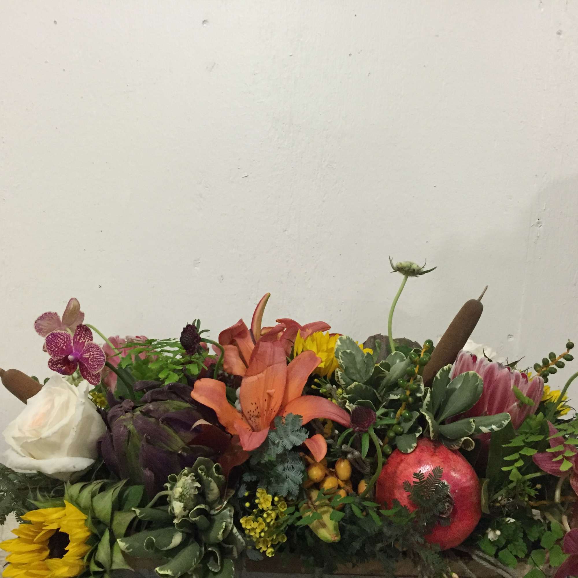 Mixed floral arrangement with lilies, roses, orchids, and a sunflower