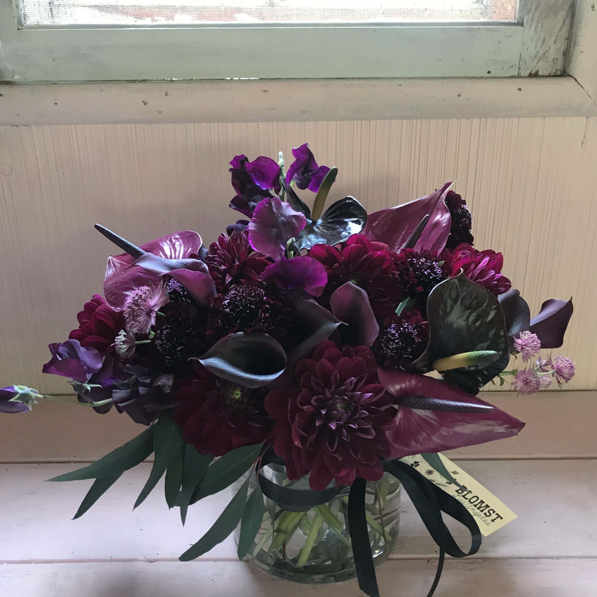 Deep purple bouquet in a clear glass vase with ribbon
