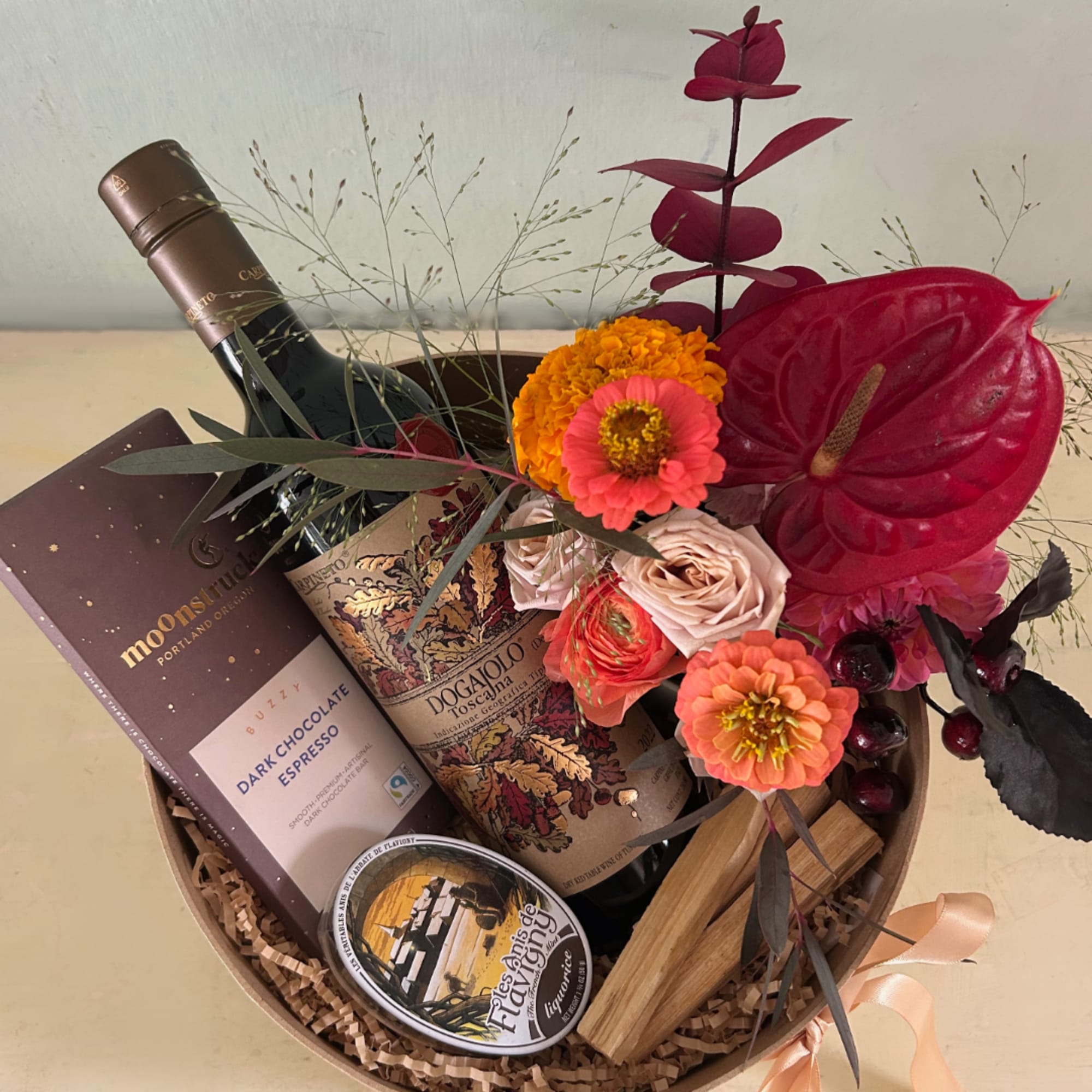 Gift basket with flowers, wine, chocolate, and a candle
