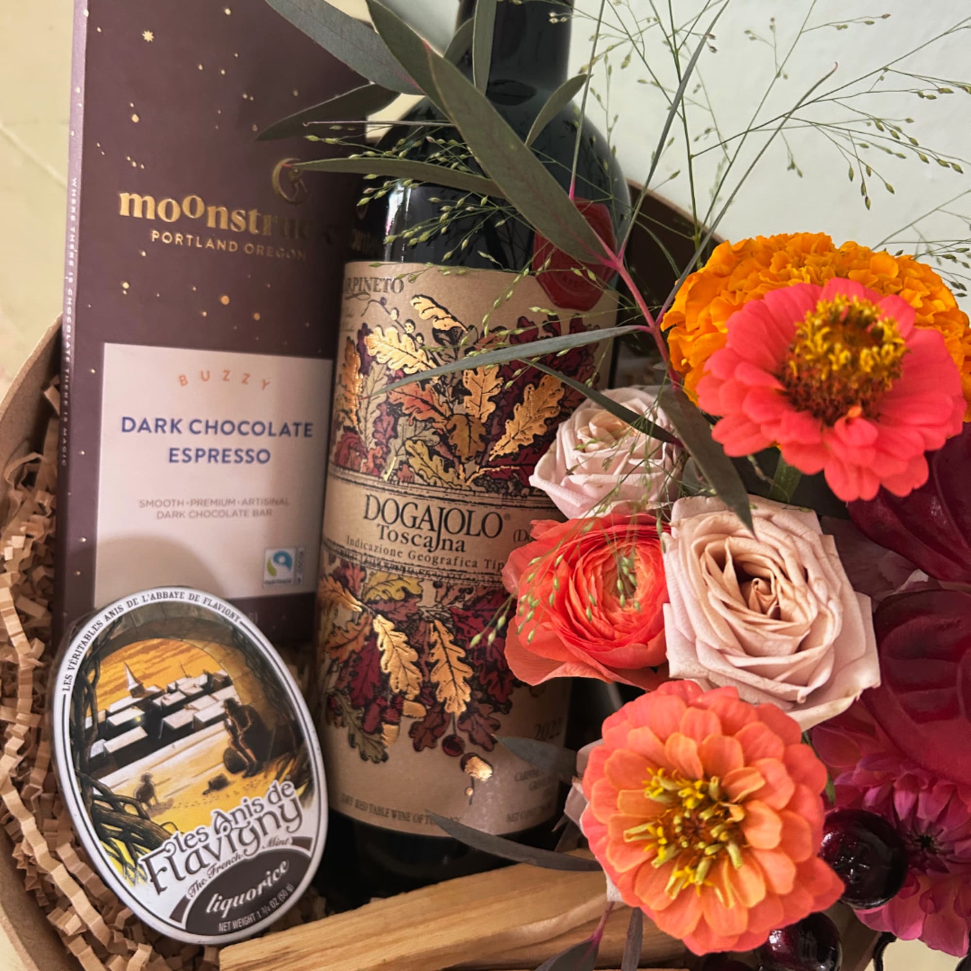Gift basket with flowers, wine, chocolate, and a liquor tin