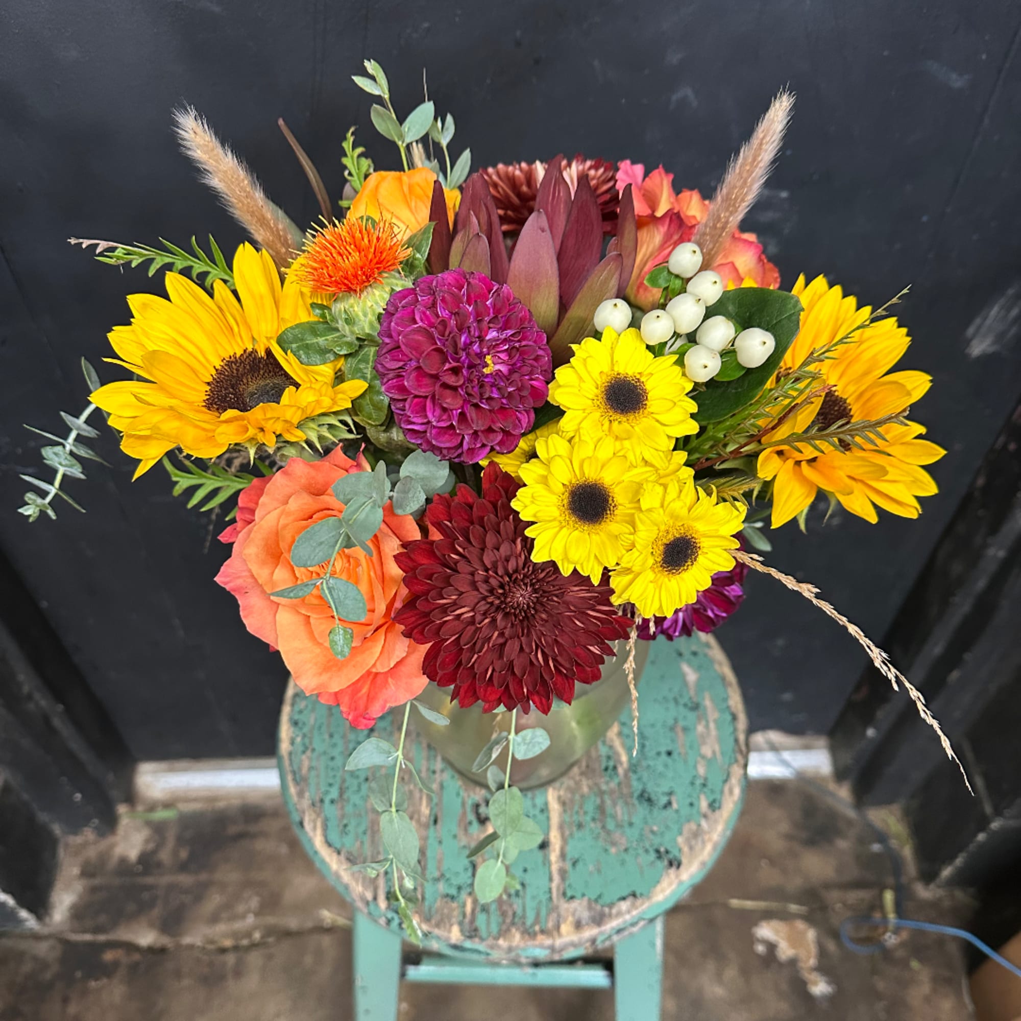 Mixed bouquet with sunflowers, roses, and chrysanthemums in a glass vase