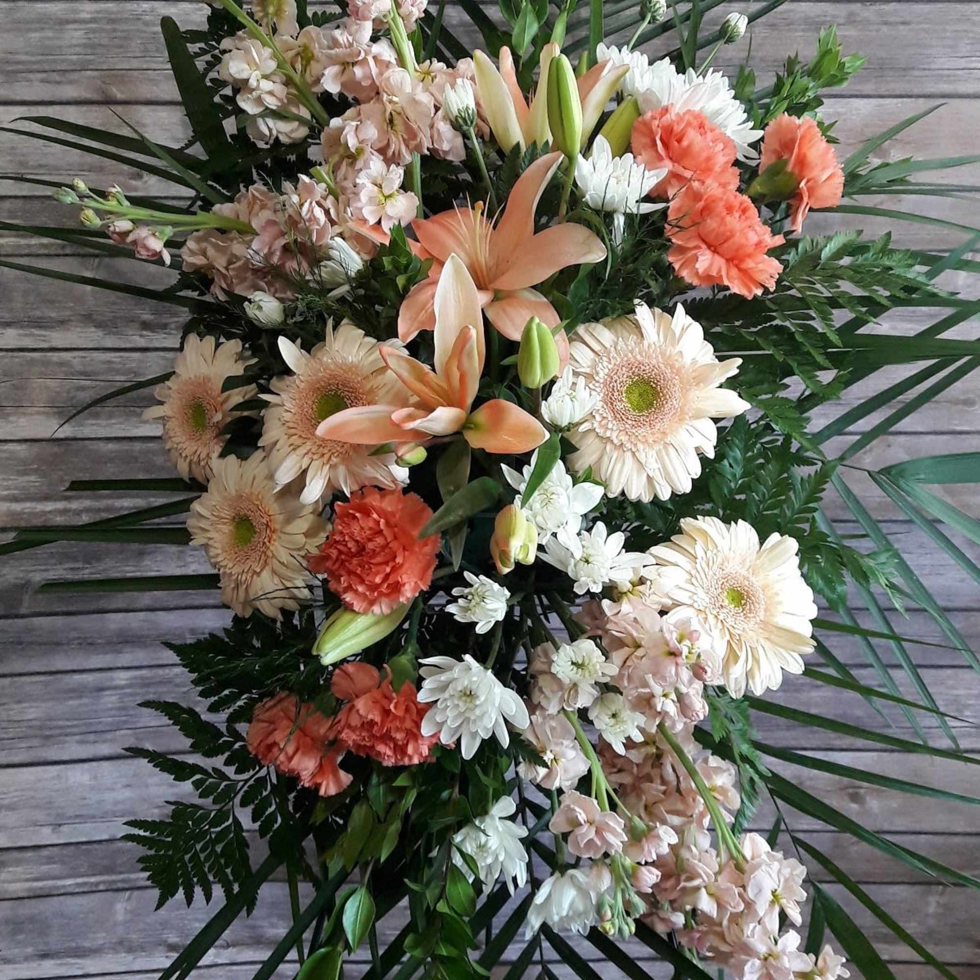 Peach lilies, white daisies, and coral carnations in a loose bouquet