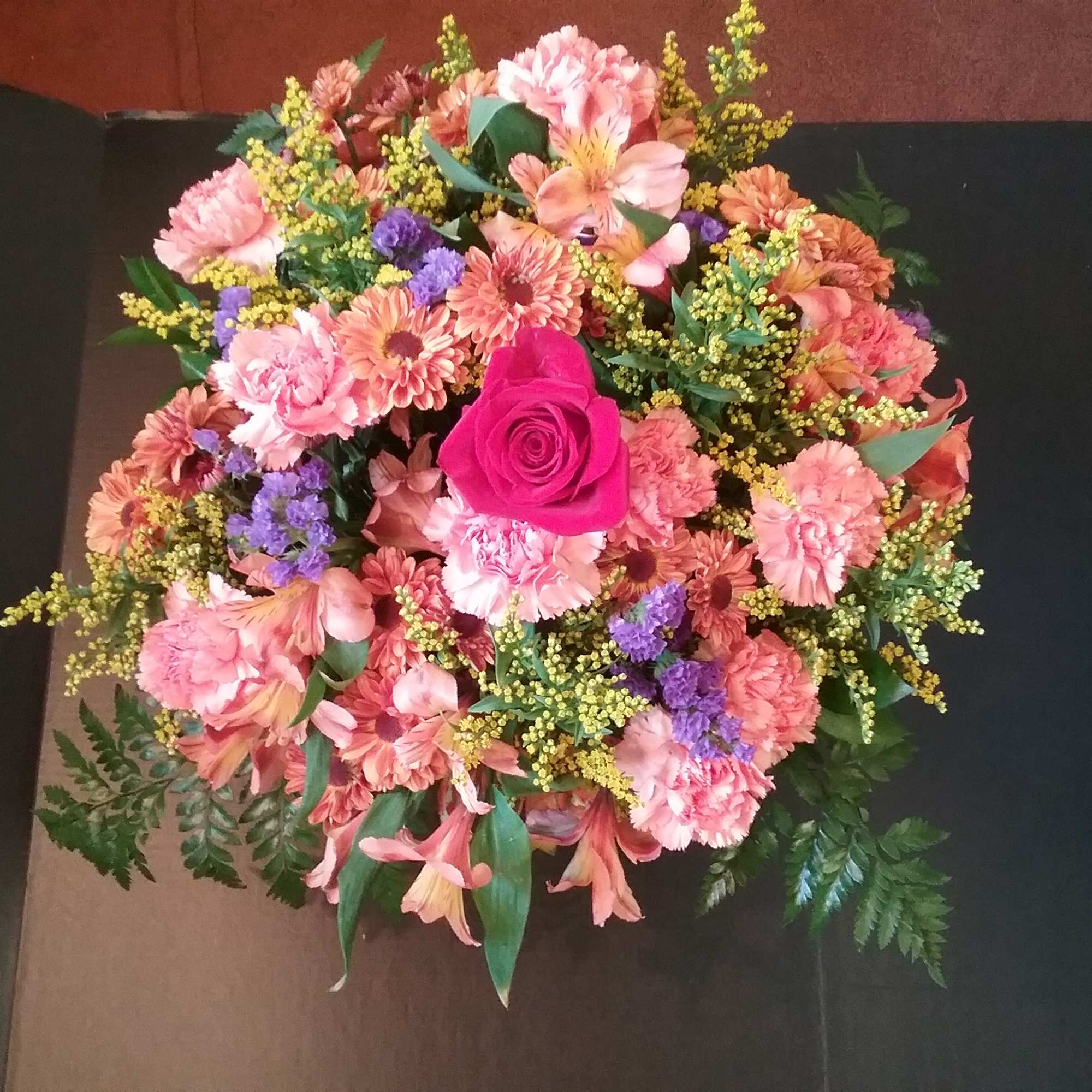 Round bouquet of pink and peach flowers with a bright pink rose center