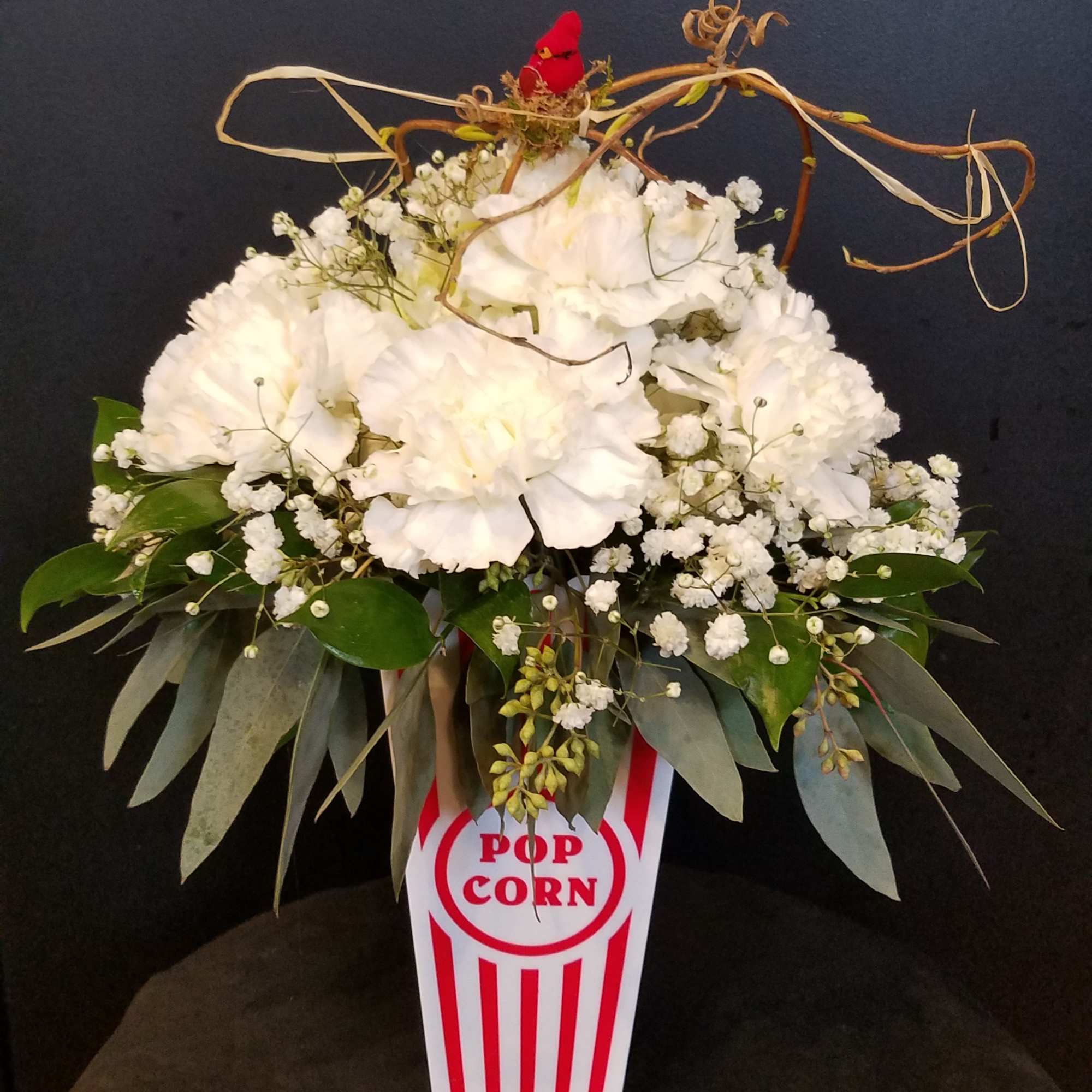White floral arrangement in a popcorn box-shaped container