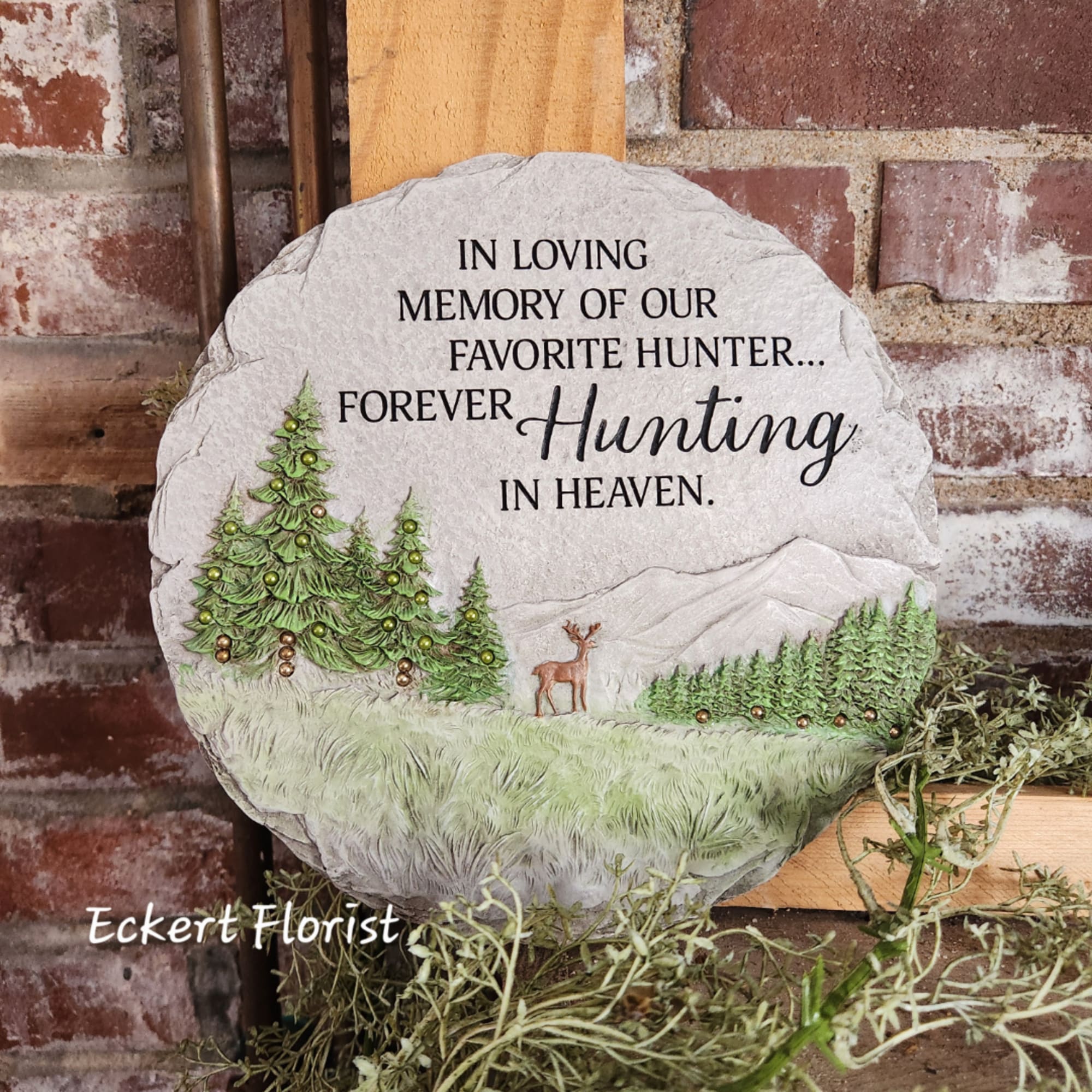 Memorial stone with hunting-themed text and pine tree relief