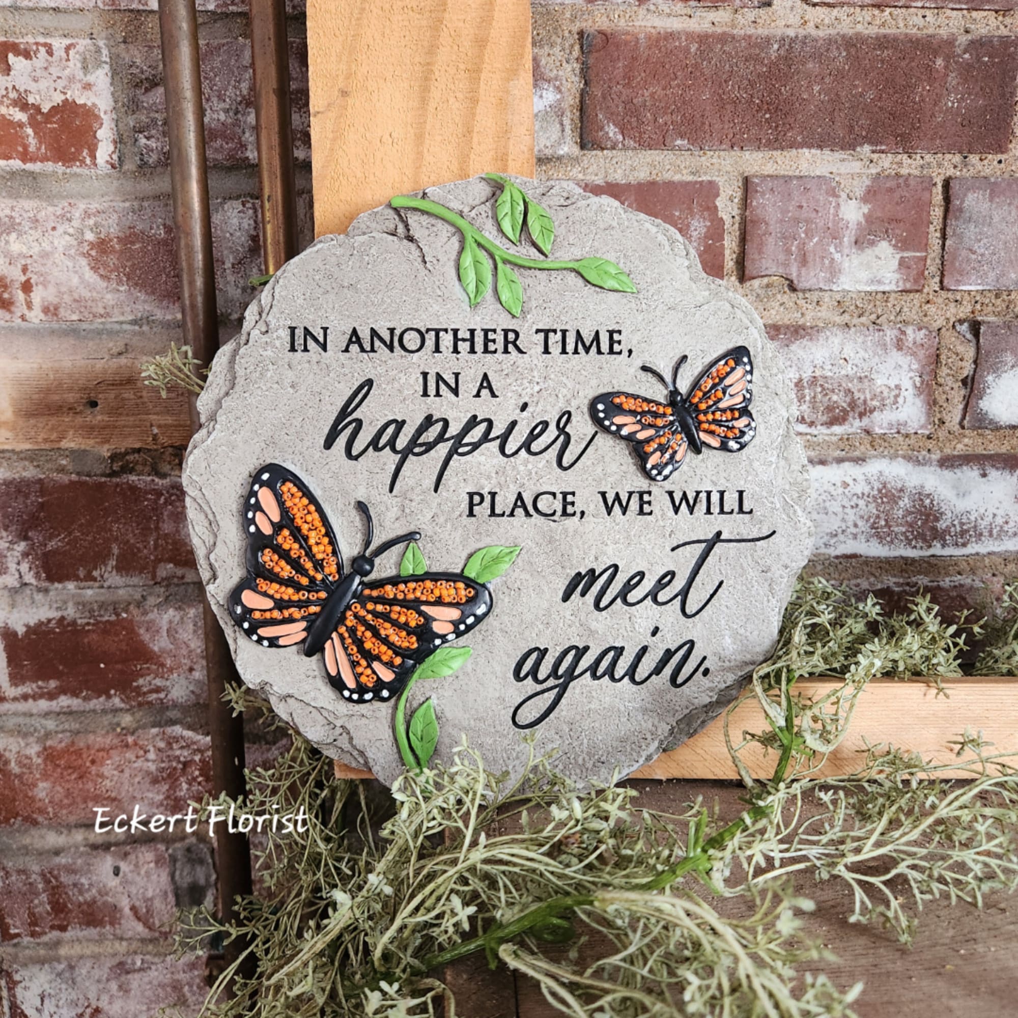 Decorative memorial stone with butterflies and the words "meet again"