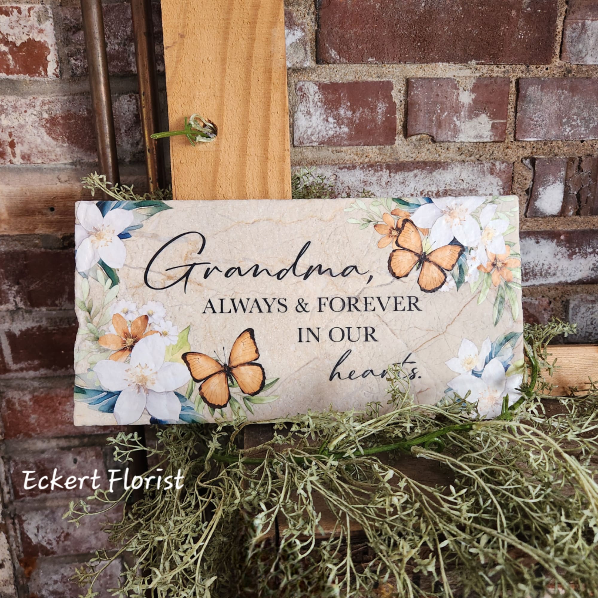 Decorative sympathy sign reading "Grandma, always & forever in our hearts" with flowers and butterflies.