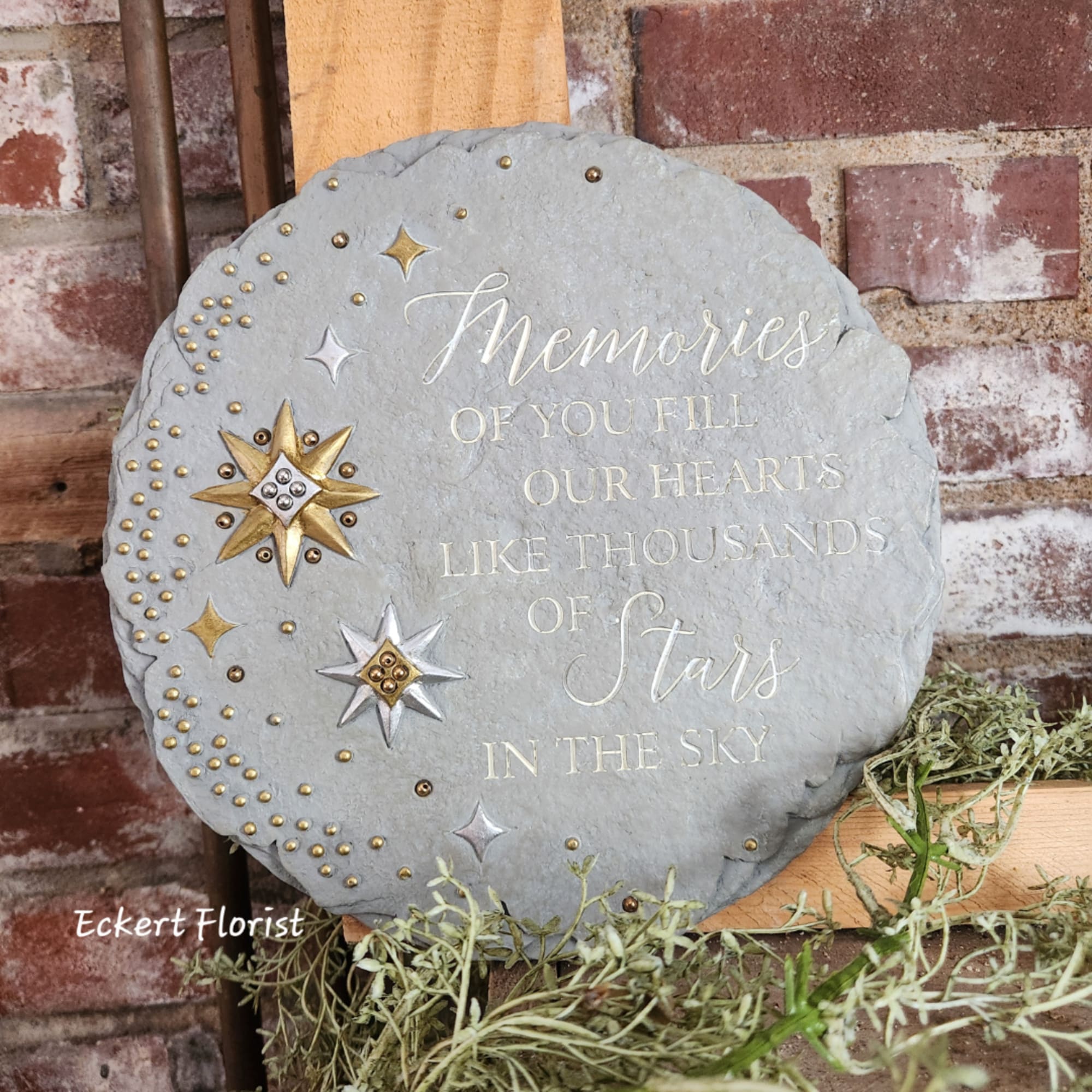 Round memorial stone plaque with star decorations and engraved text