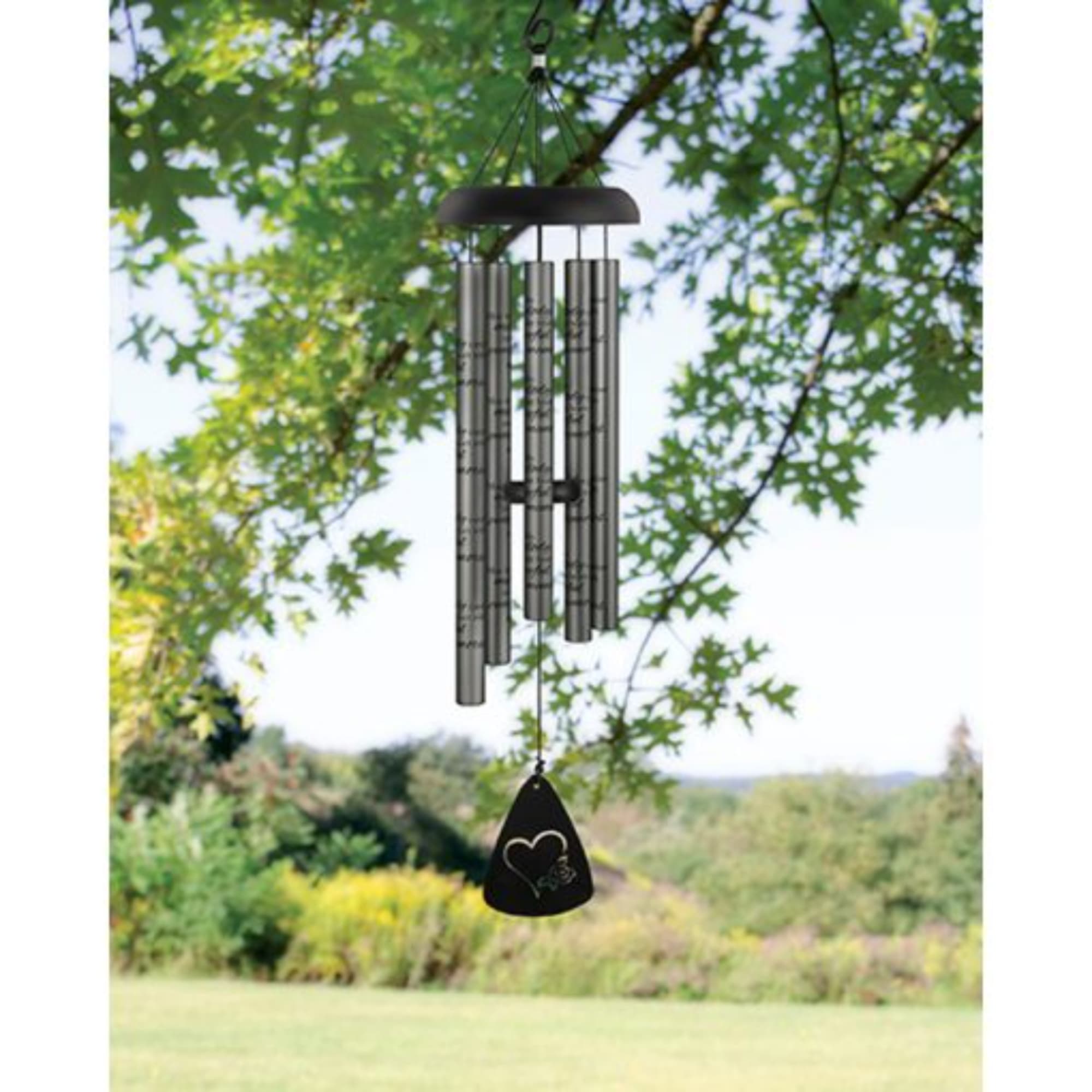 Black wind chime hanging outdoors in front of trees
