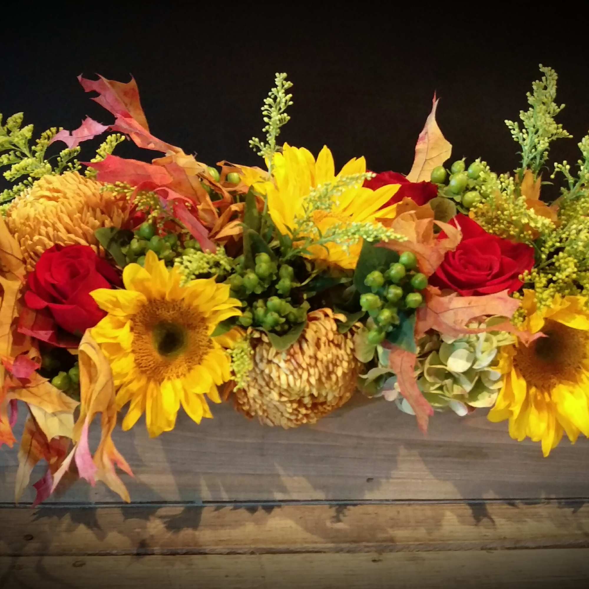 Autumn floral arrangement with sunflowers and red roses in a rectangular wooden box