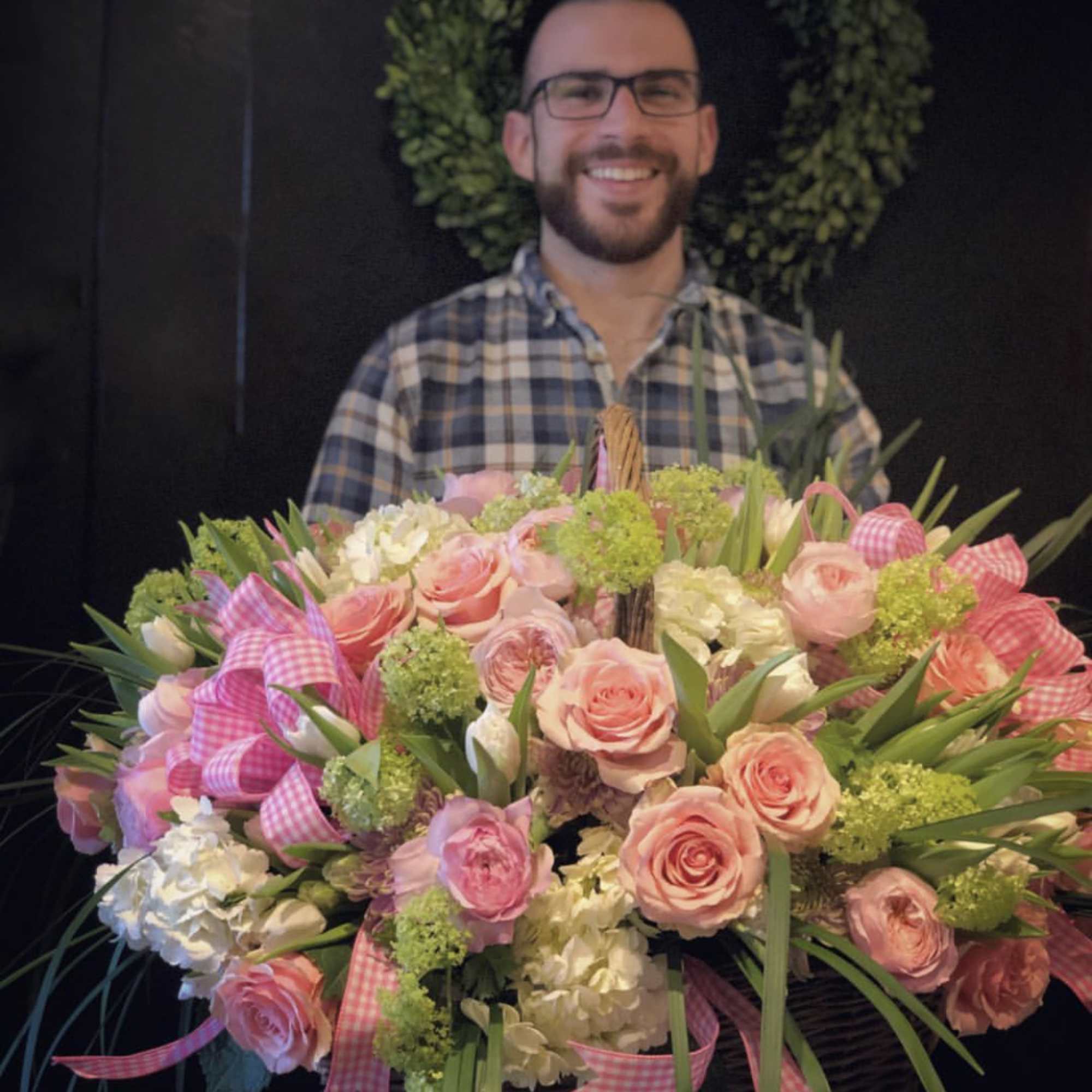 Large basket arrangement of pink roses and white blooms with gingham ribbons