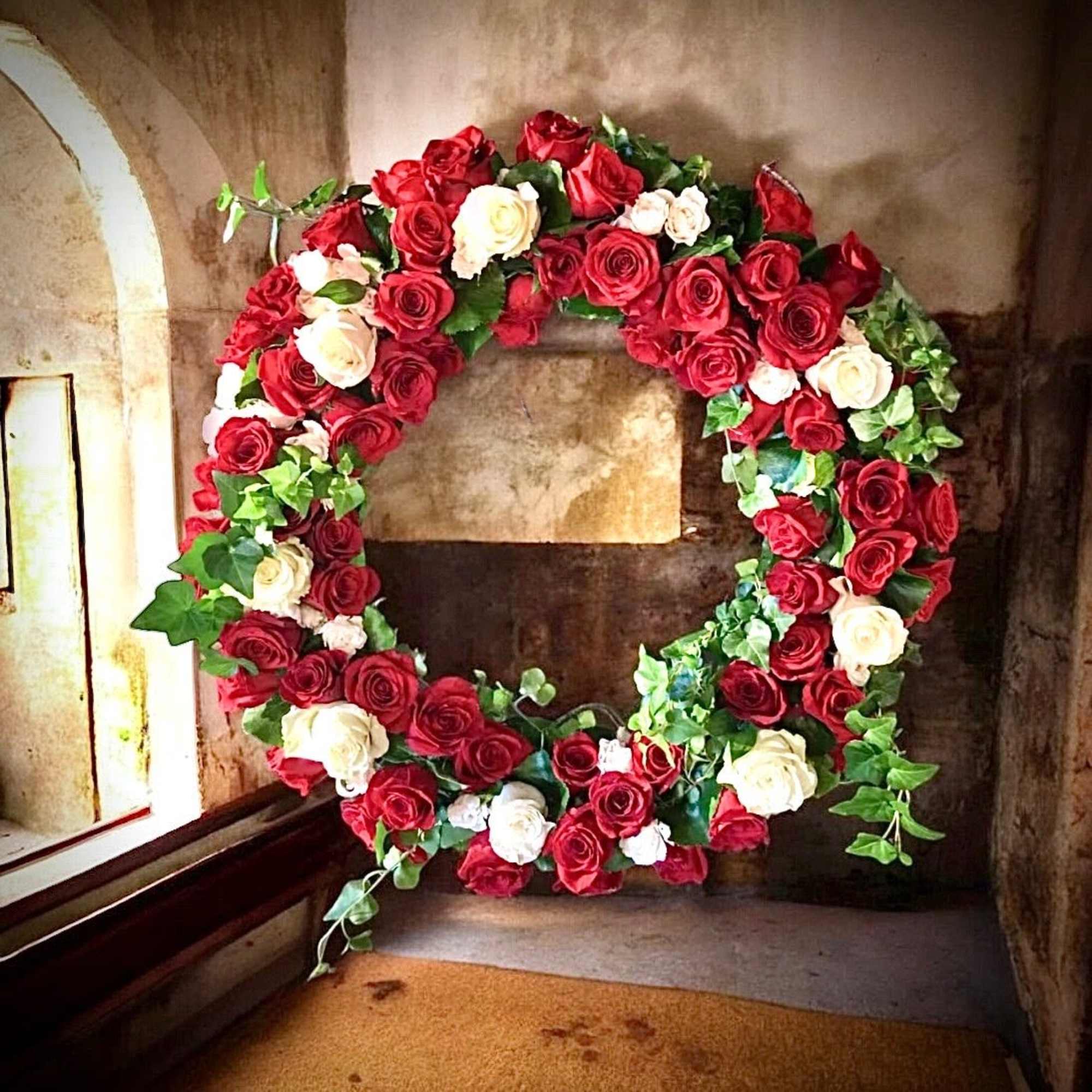 Circular wreath of red and white roses with ivy greenery