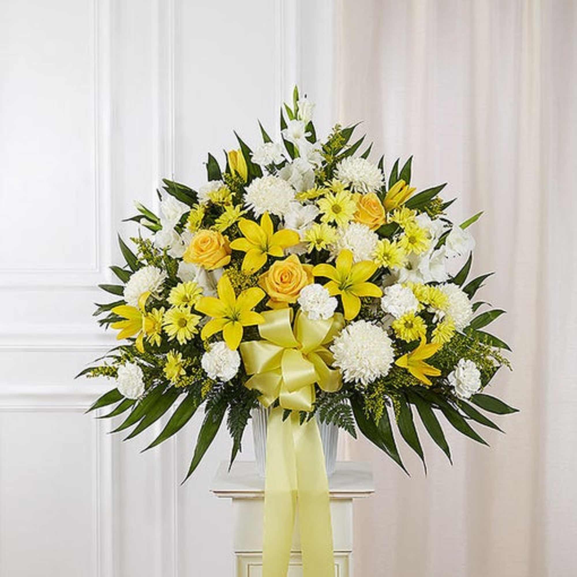 Yellow and white floral spray with a ribbon bow on a stand