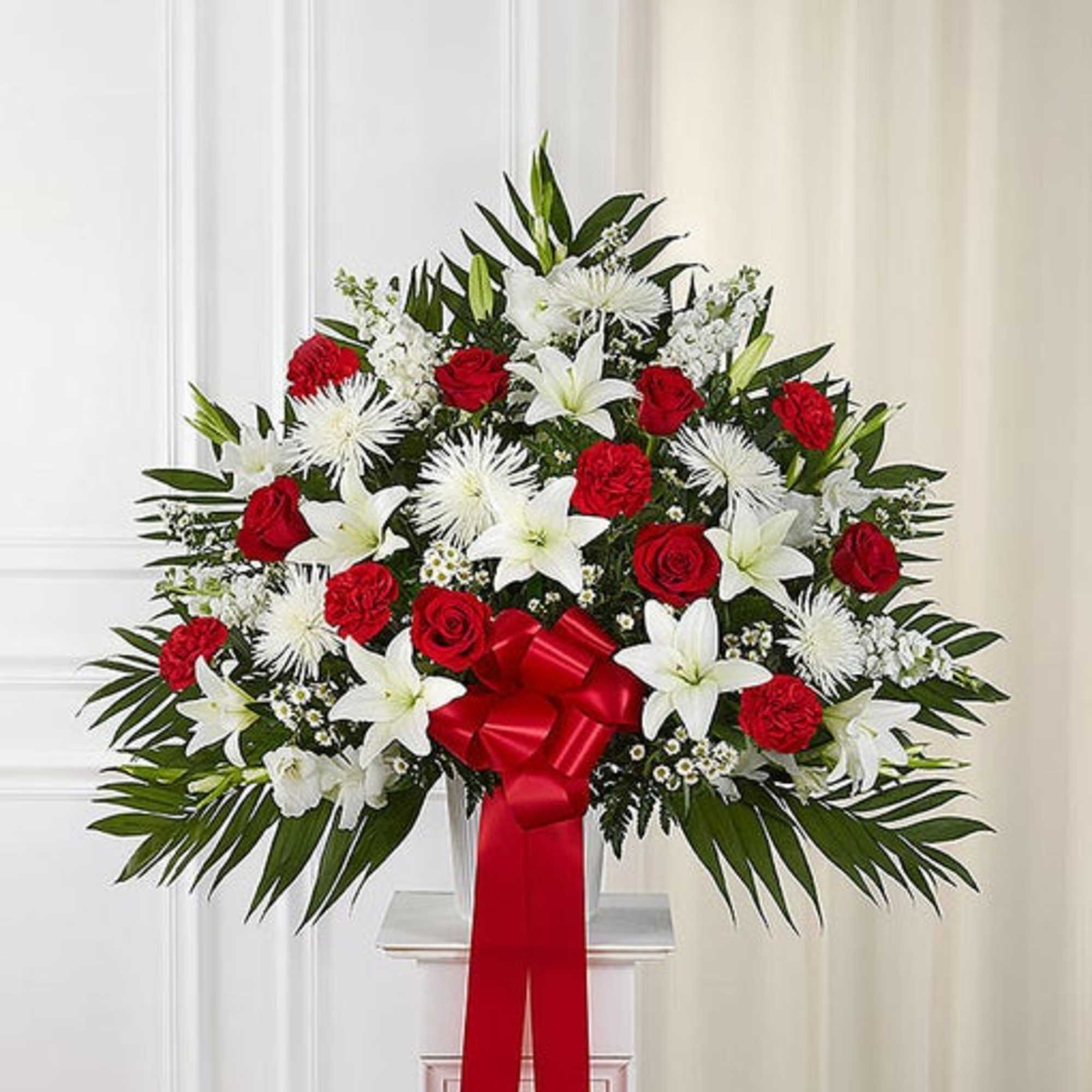 Red roses and white lilies in a standing arrangement with a red ribbon