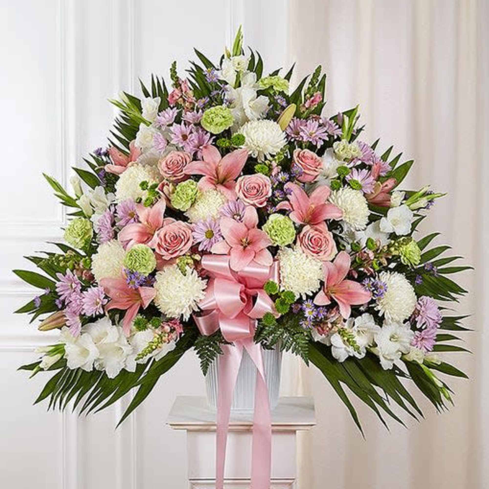 Large pink and white floral standing spray with a pink ribbon bow