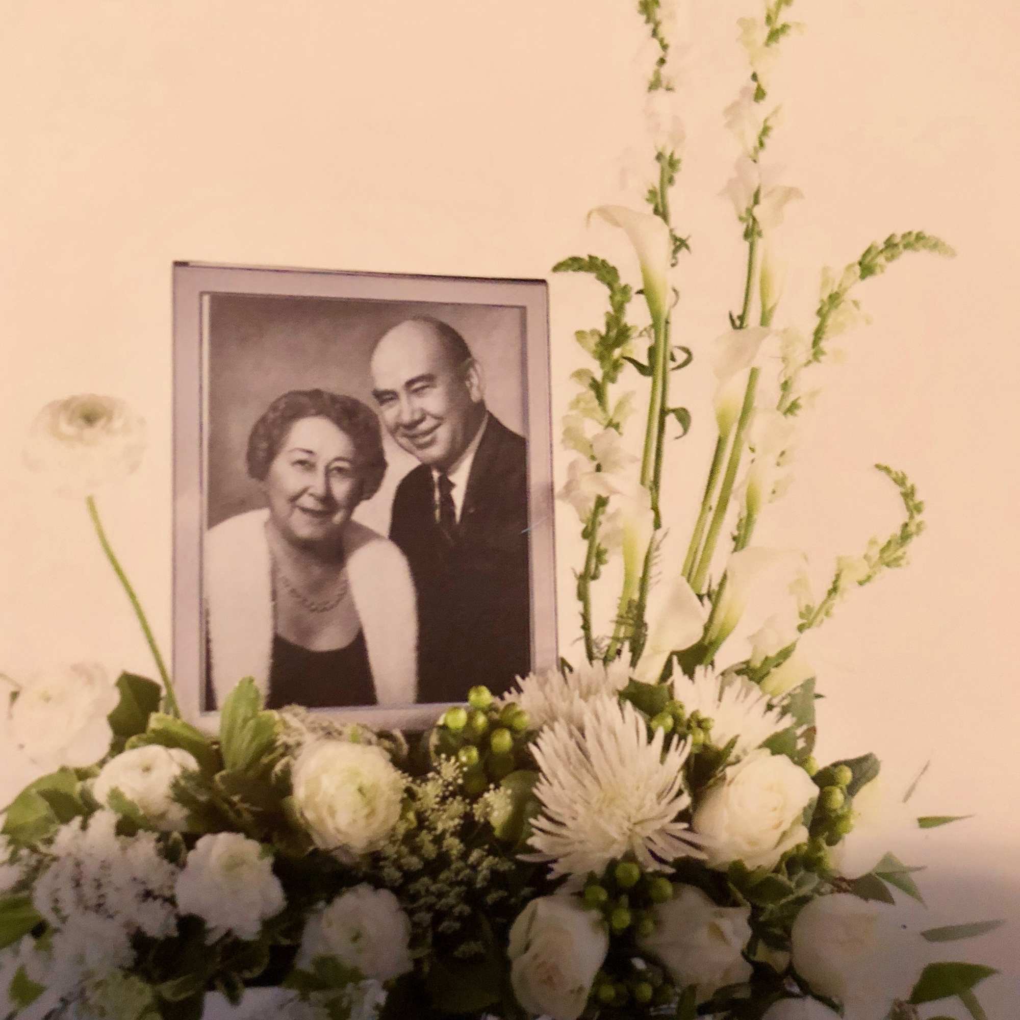 White floral arrangement with a framed portrait centerpiece