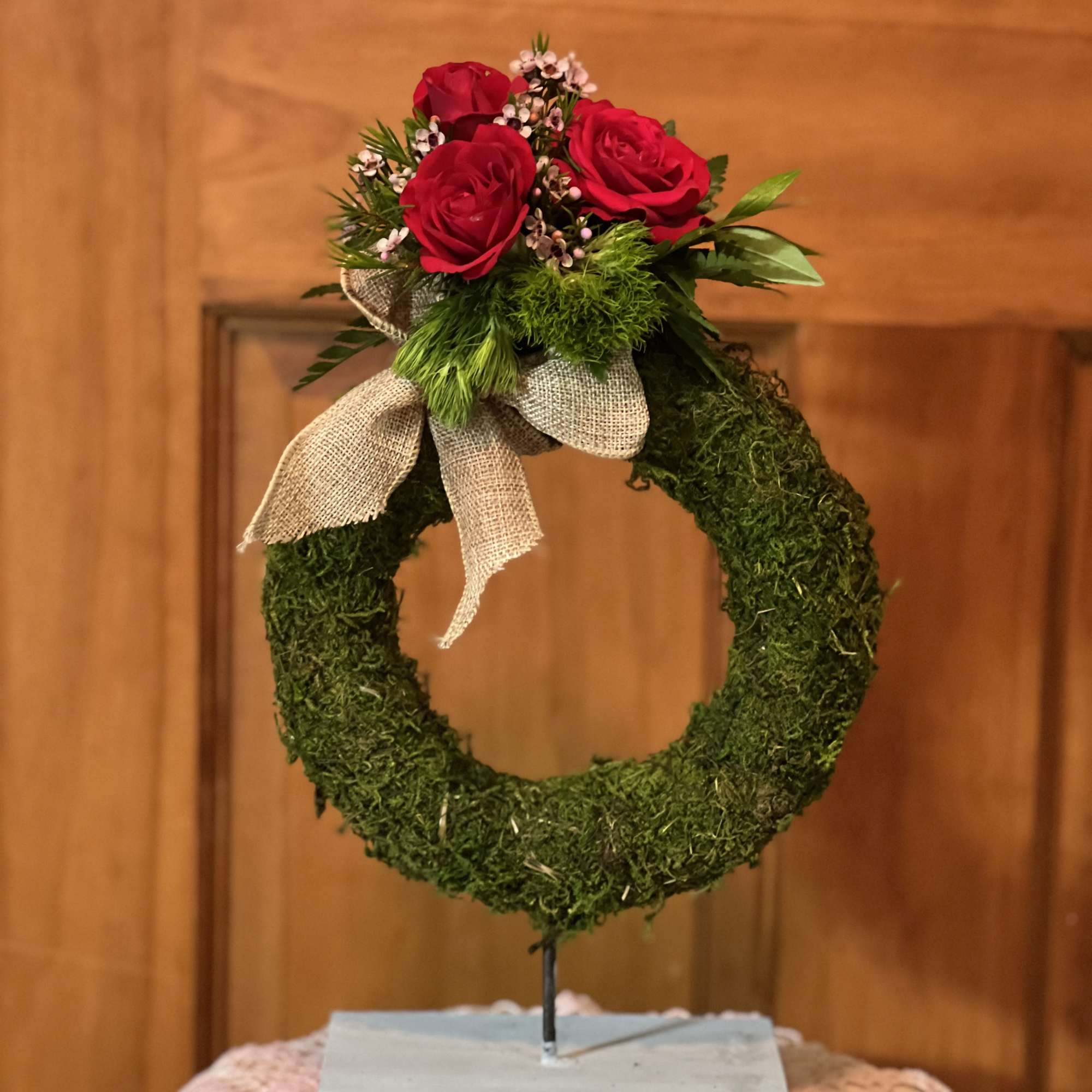 Red roses on a moss wreath with a burlap bow