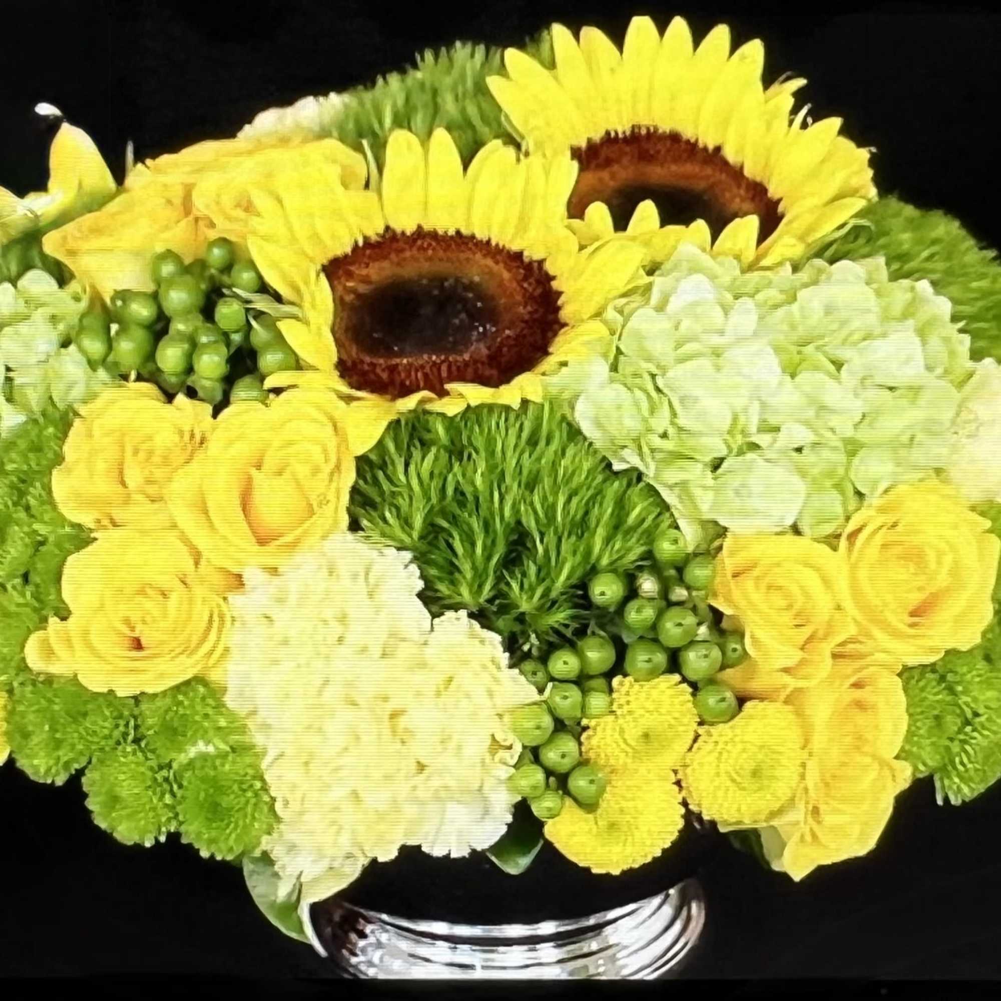 Two tall sunflowers rise above a compact, rounded centerpiece-an upbeat flower arrangement