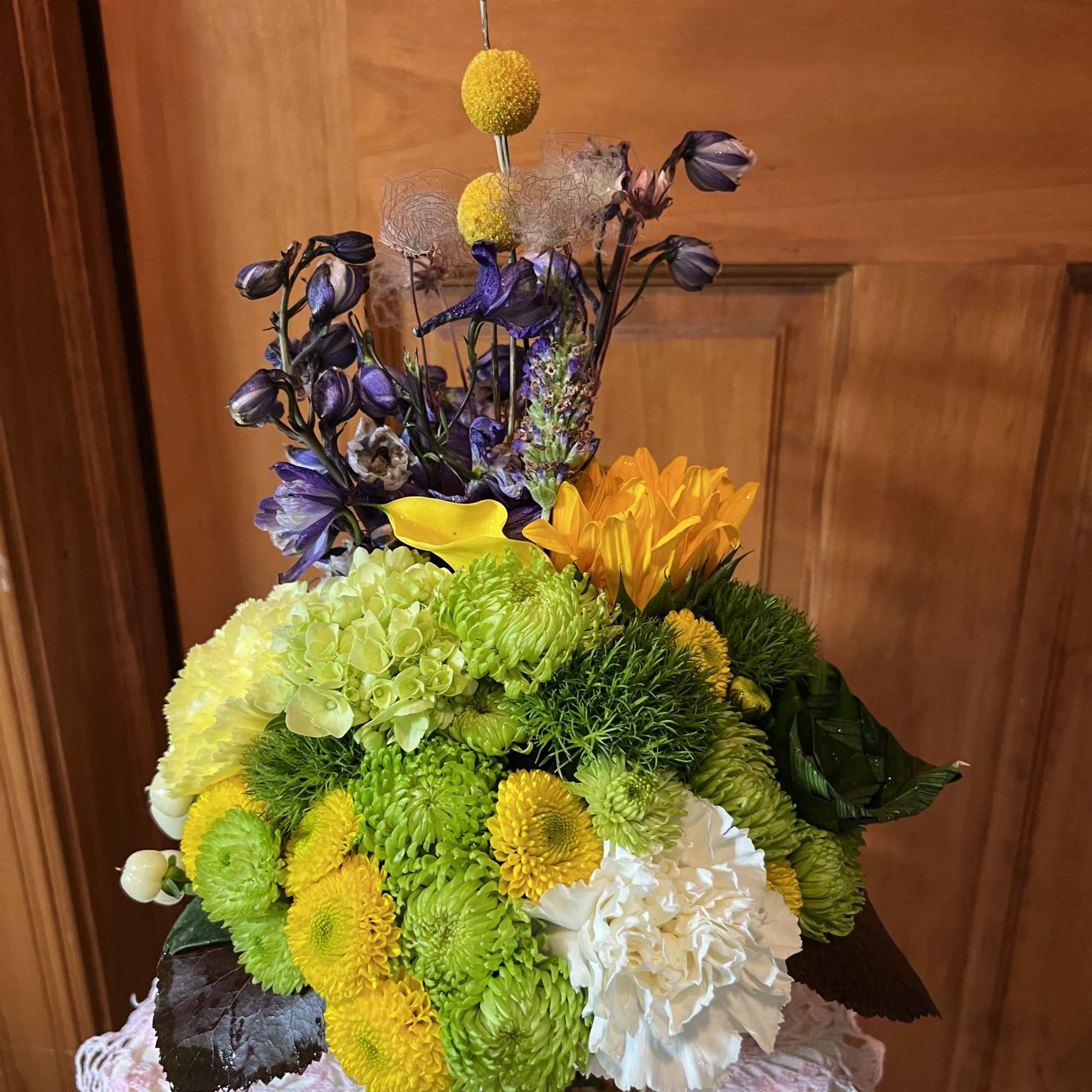 Two tall sunflowers rise above a compact, rounded centerpiece-an upbeat flower arrangement