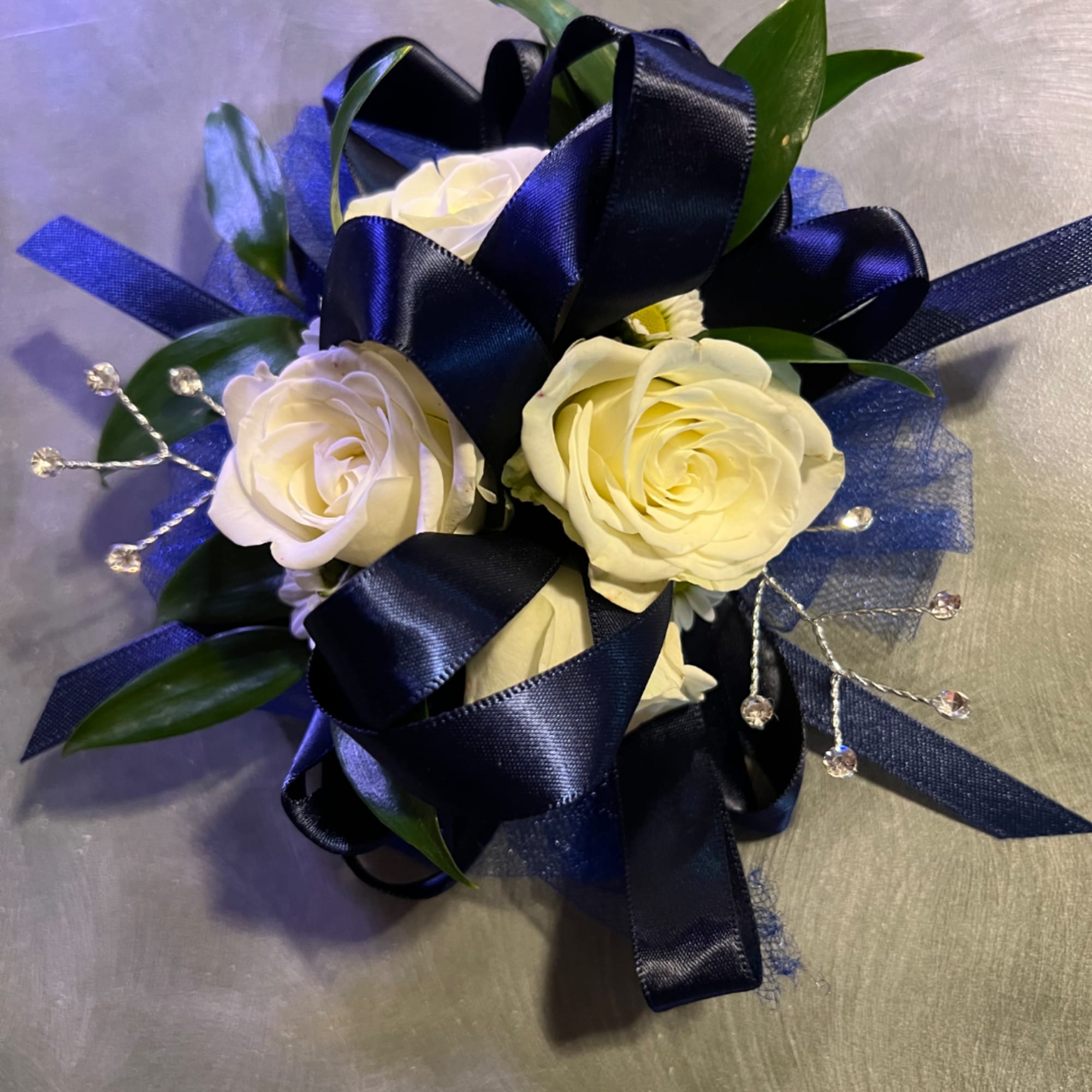 White rose corsage with navy ribbon and blue mesh accents