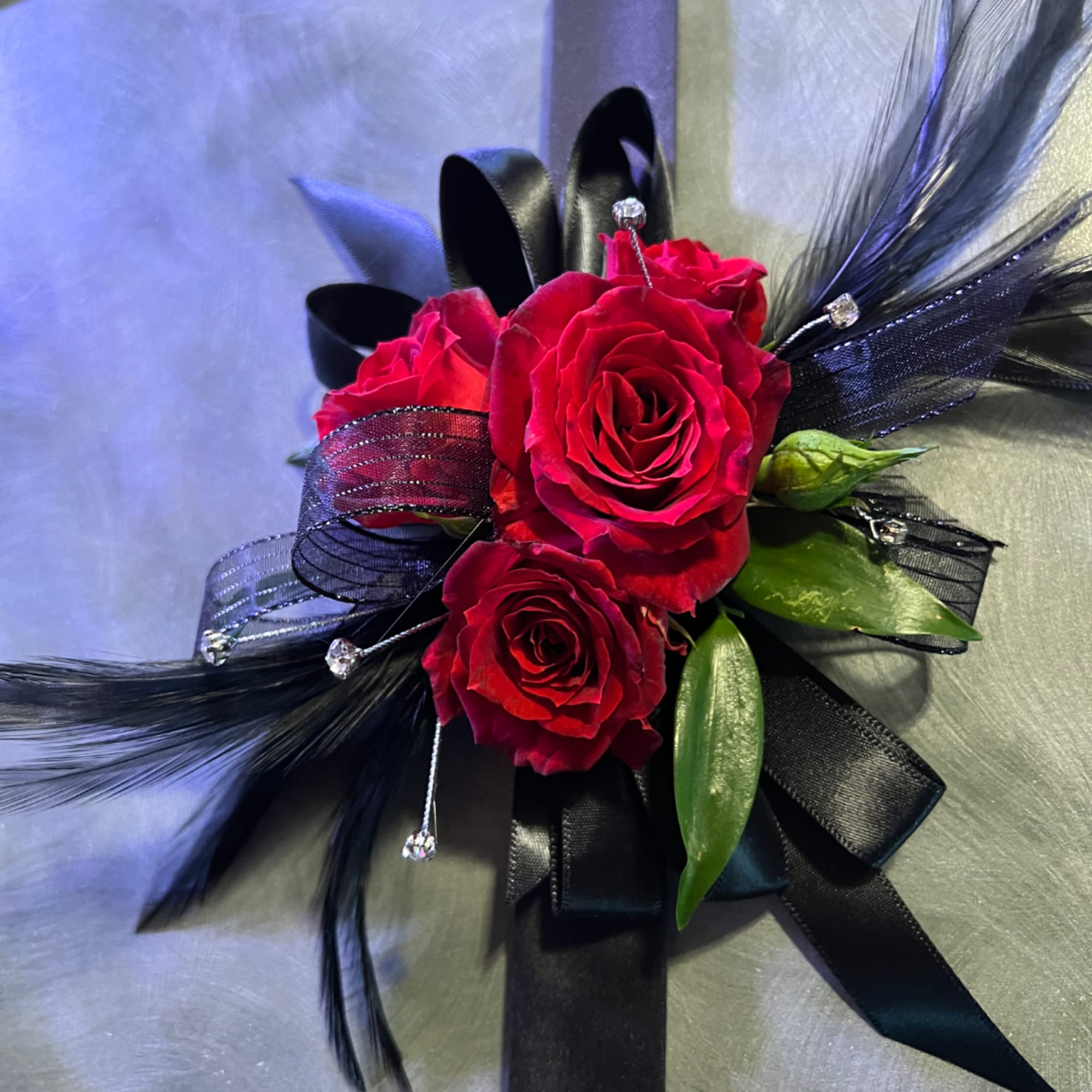 Red rose corsage with black ribbon and feathers