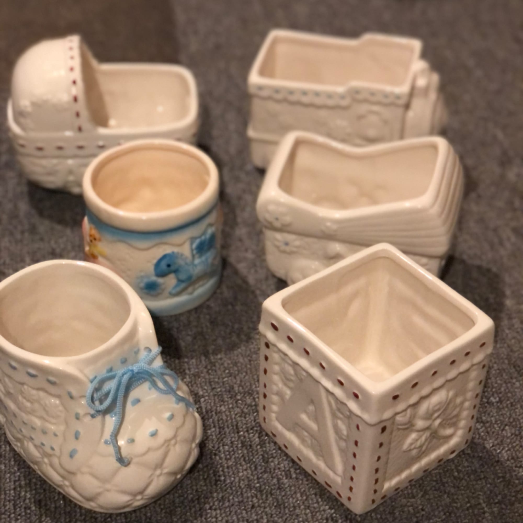 Five small ceramic planters and decorative pots on a carpeted surface