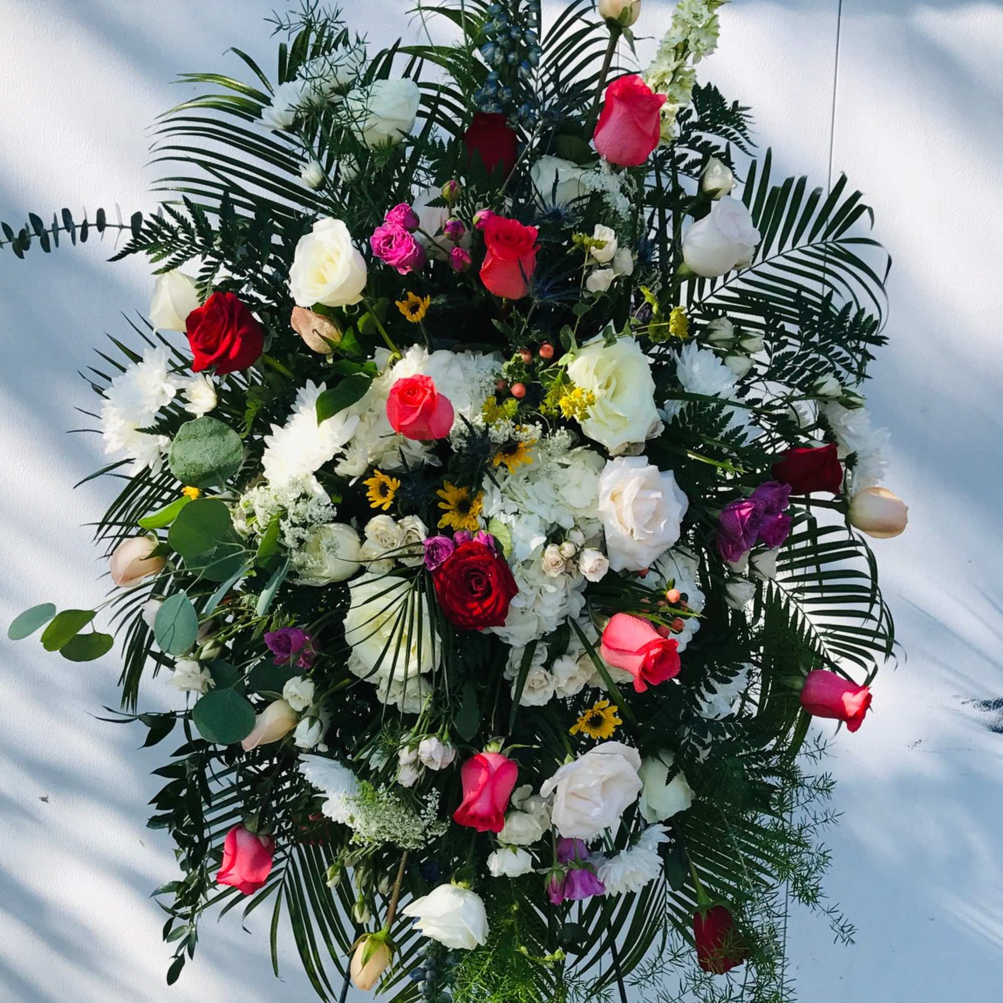 Large standing floral spray with red, white, and pink roses