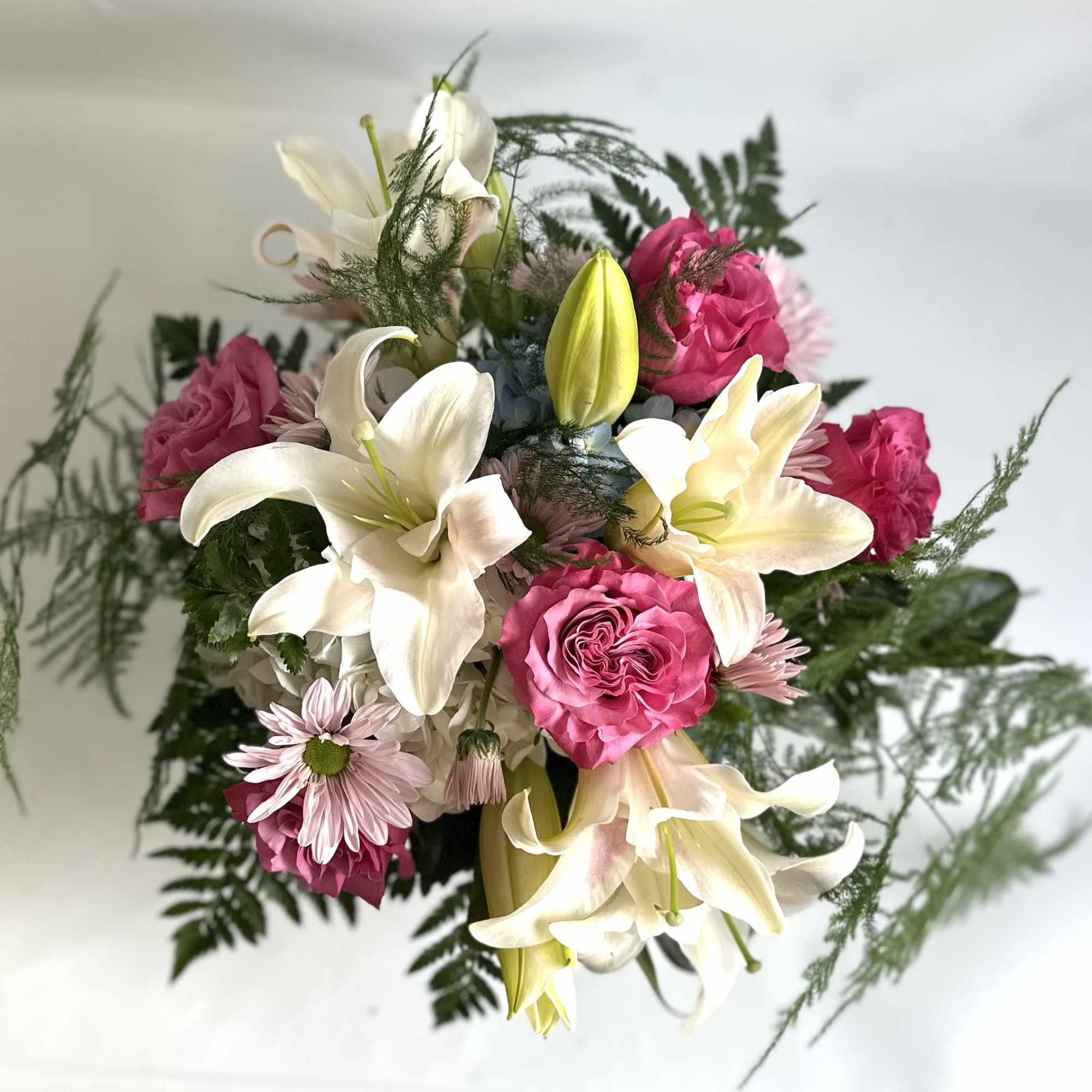 Bouquet of white lilies and pink roses with fern-like greenery