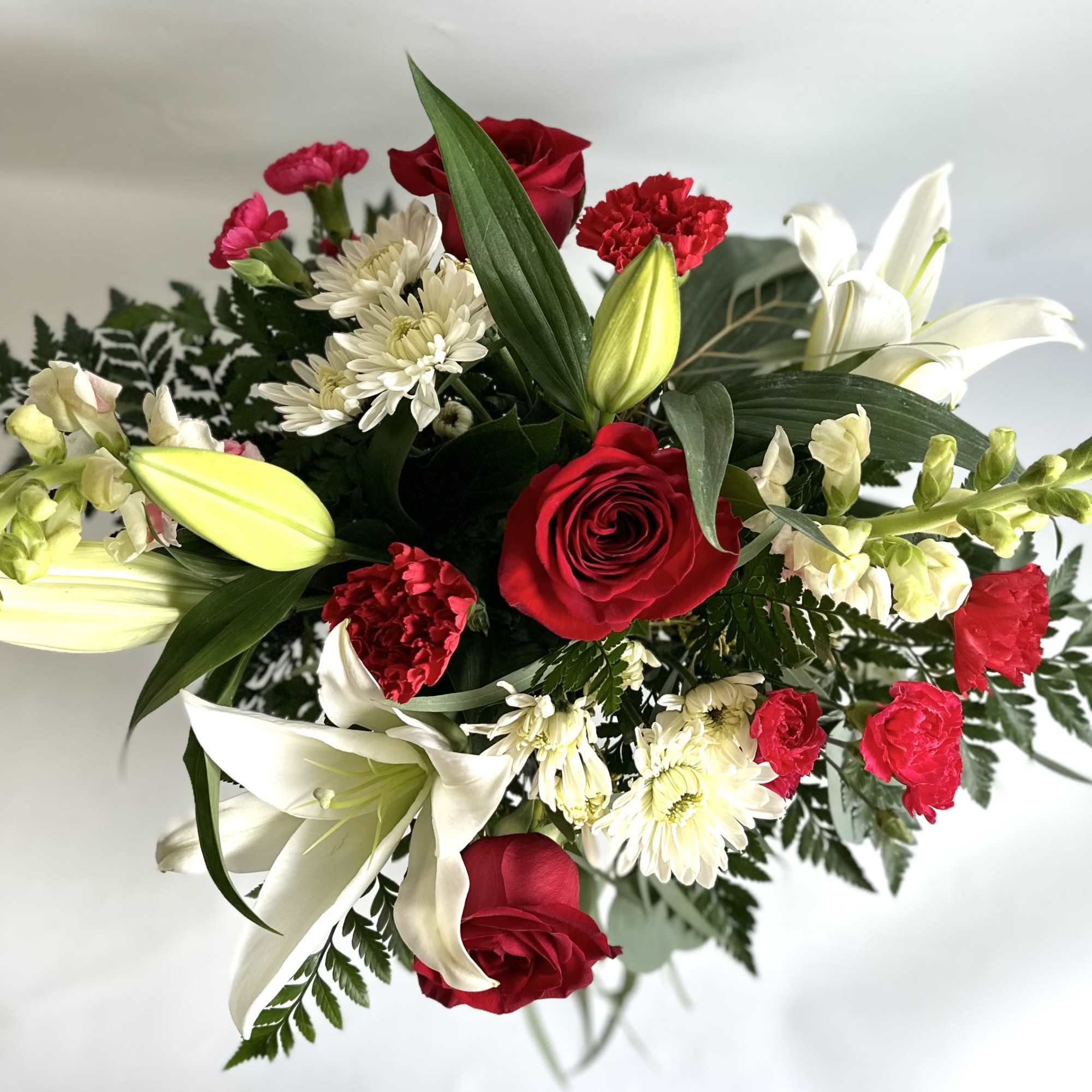 Cute red jar vase filled with hydrangeas, lilies, eucalyptus, roses, mums and
