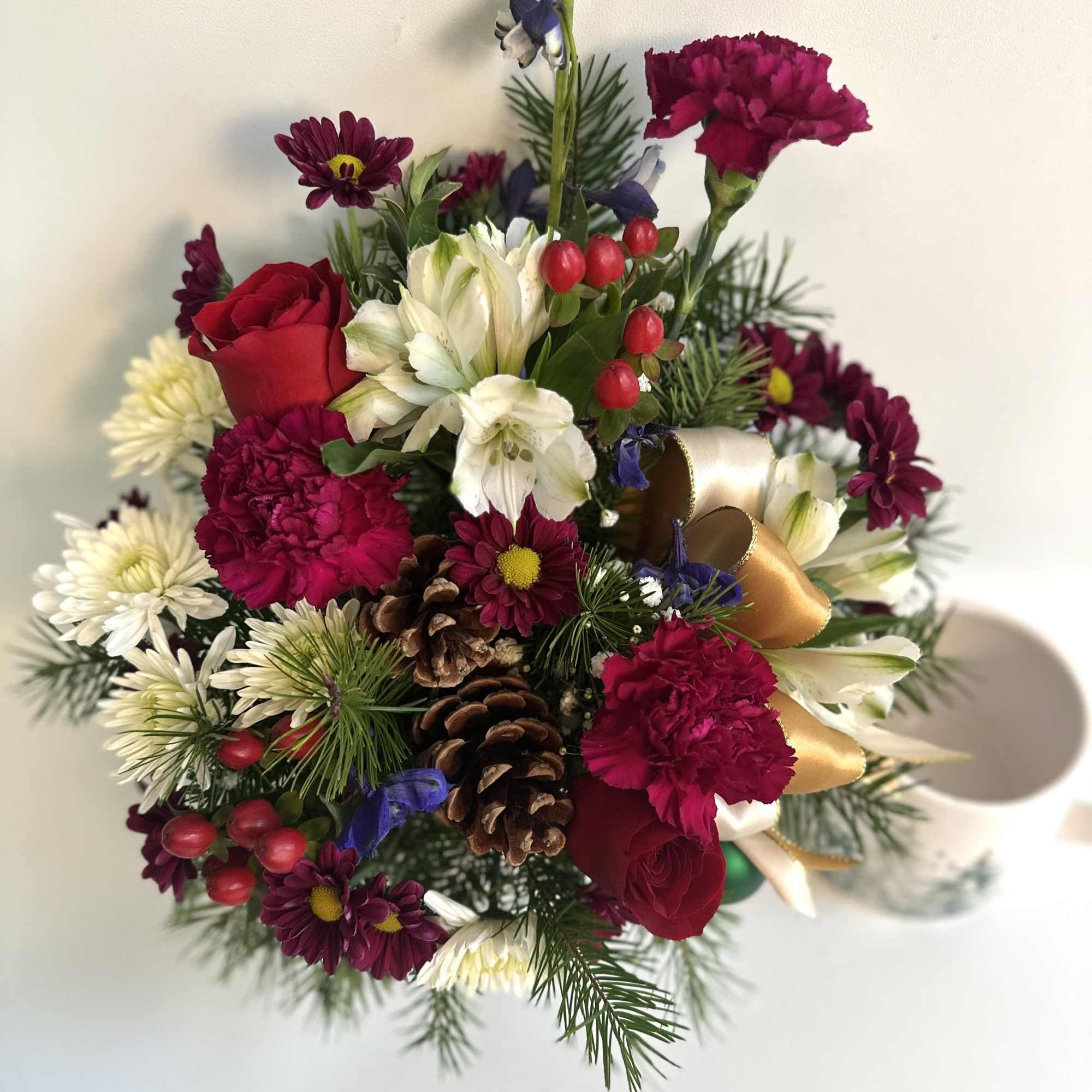 Bouquet of red, white, and purple flowers with pinecones and ribbon