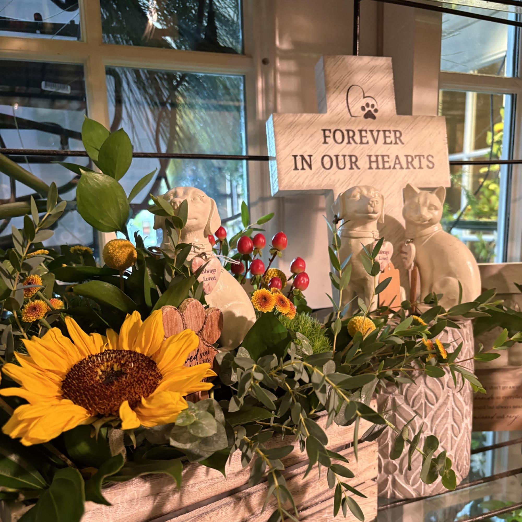 Sunflower arrangement with greenery and memorial dog and cat figurines