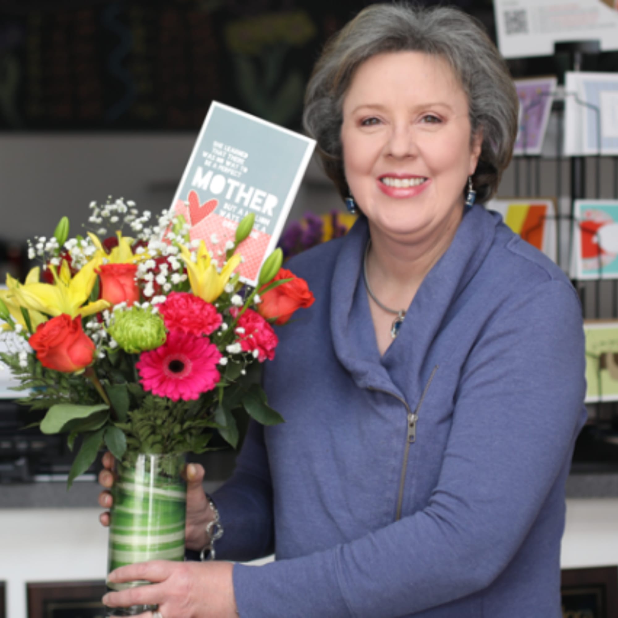 Woman holding a colorful bouquet in a striped glass vase