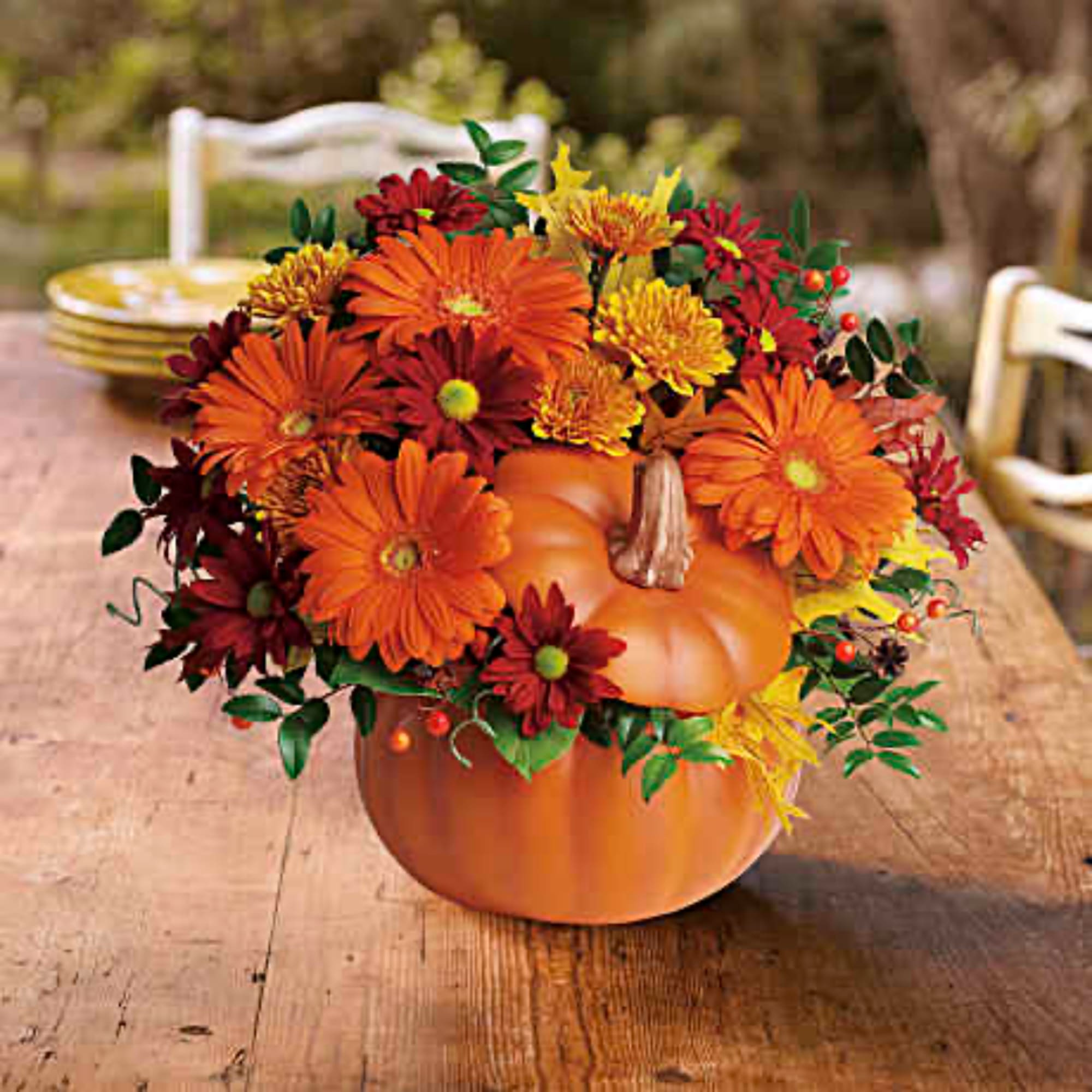 Orange pumpkin centerpiece with red and yellow flowers