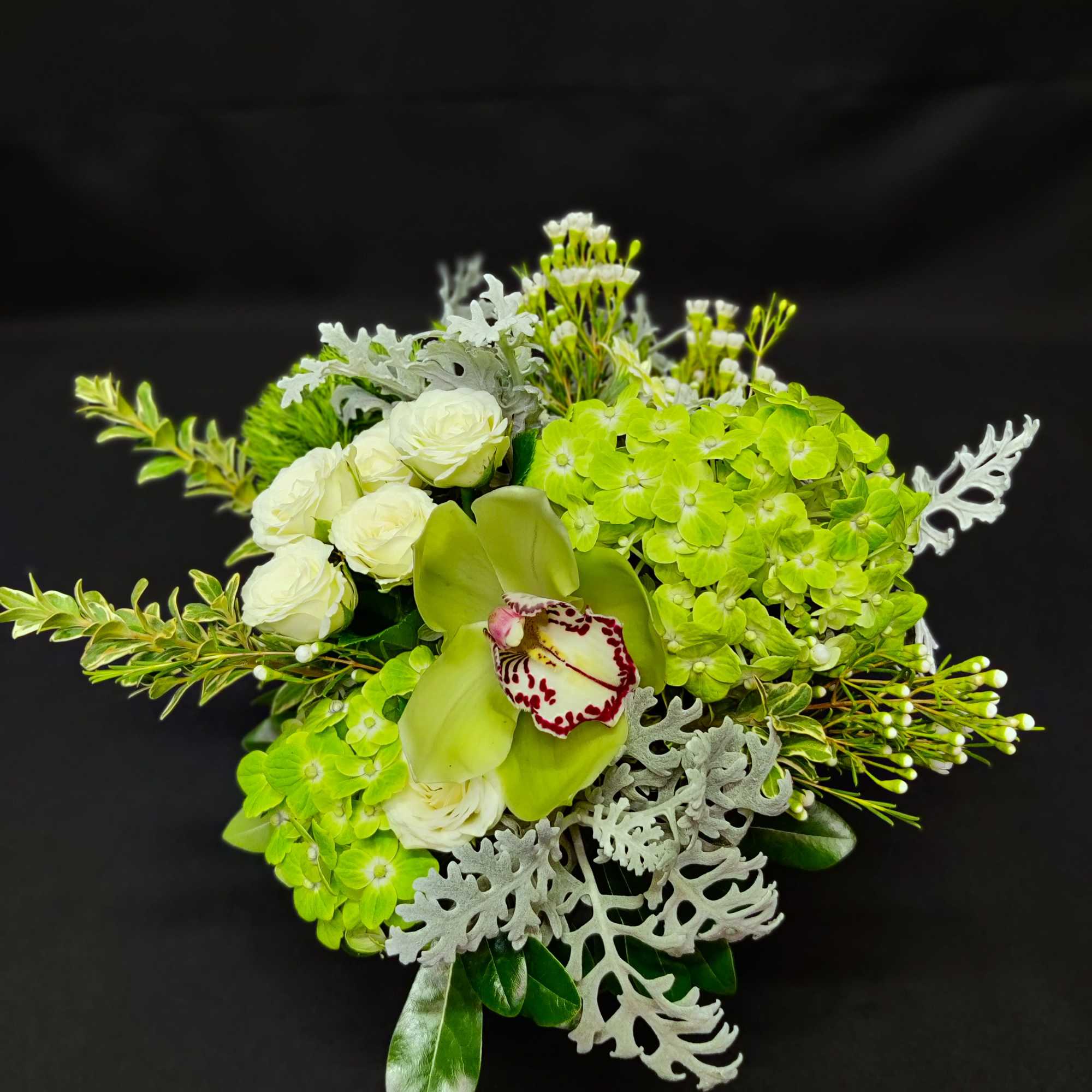 Green and white floral bouquet with orchids and roses