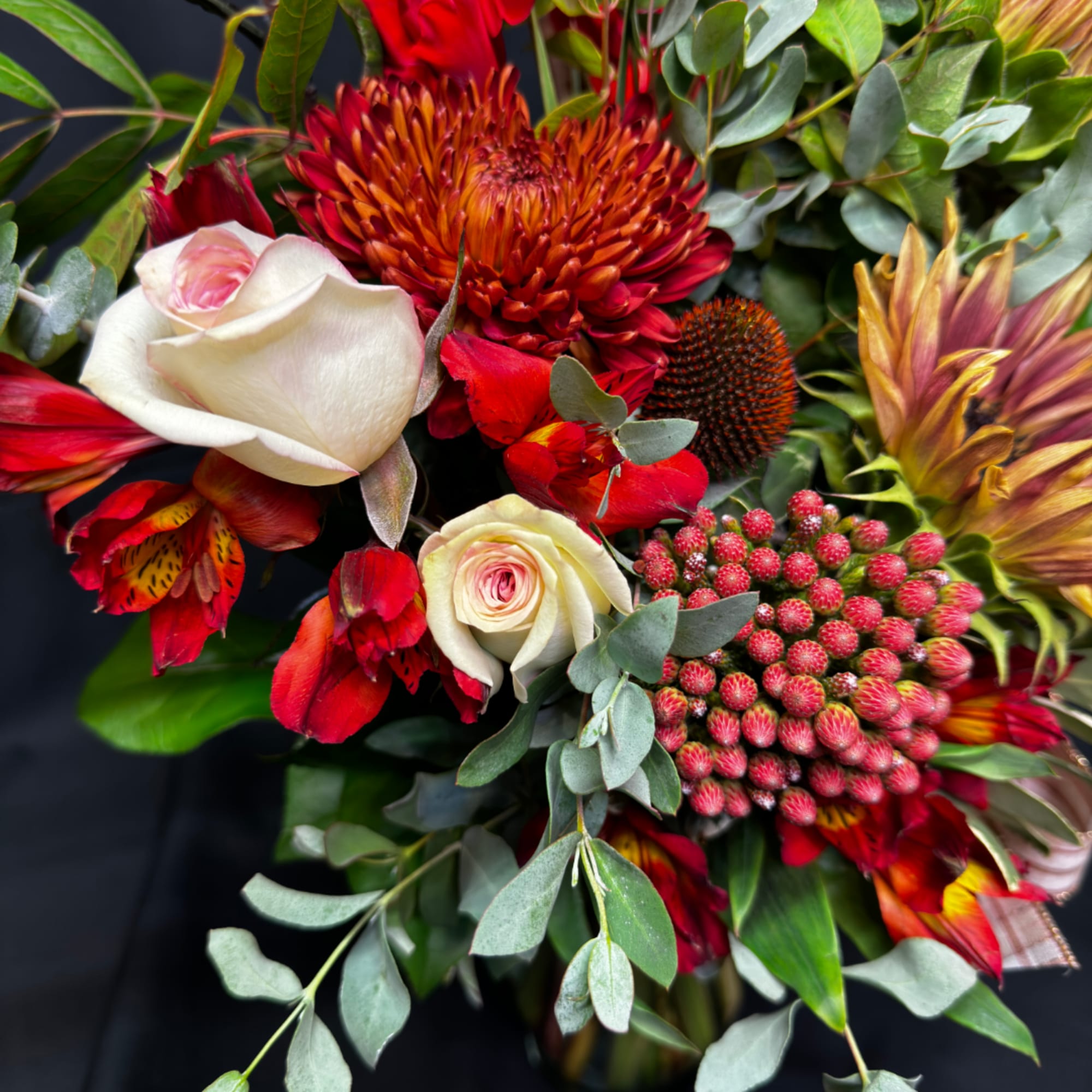 Bouquet with white roses, red-orange blooms, and eucalyptus foliage