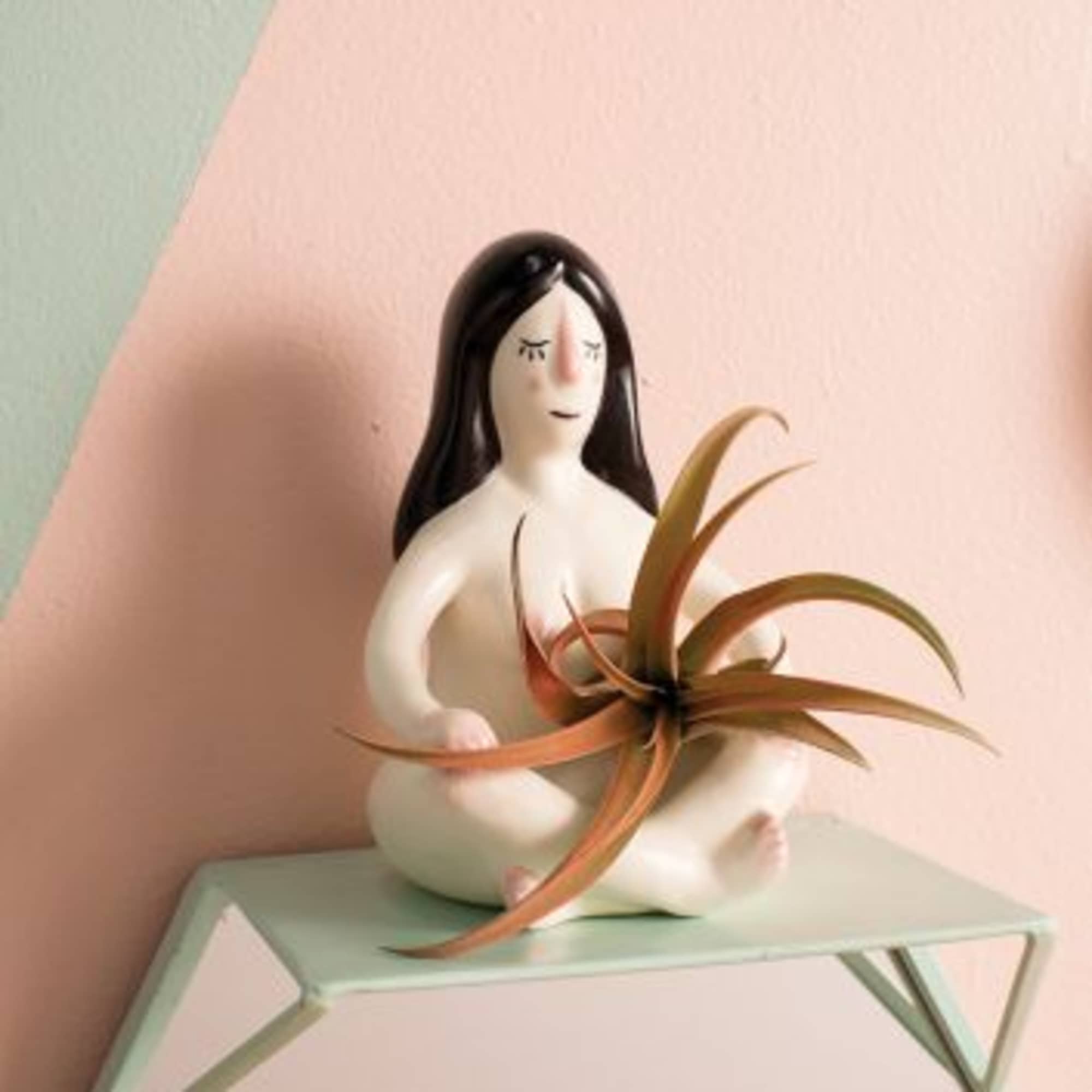 Ceramic figurine of a seated woman holding an air plant
