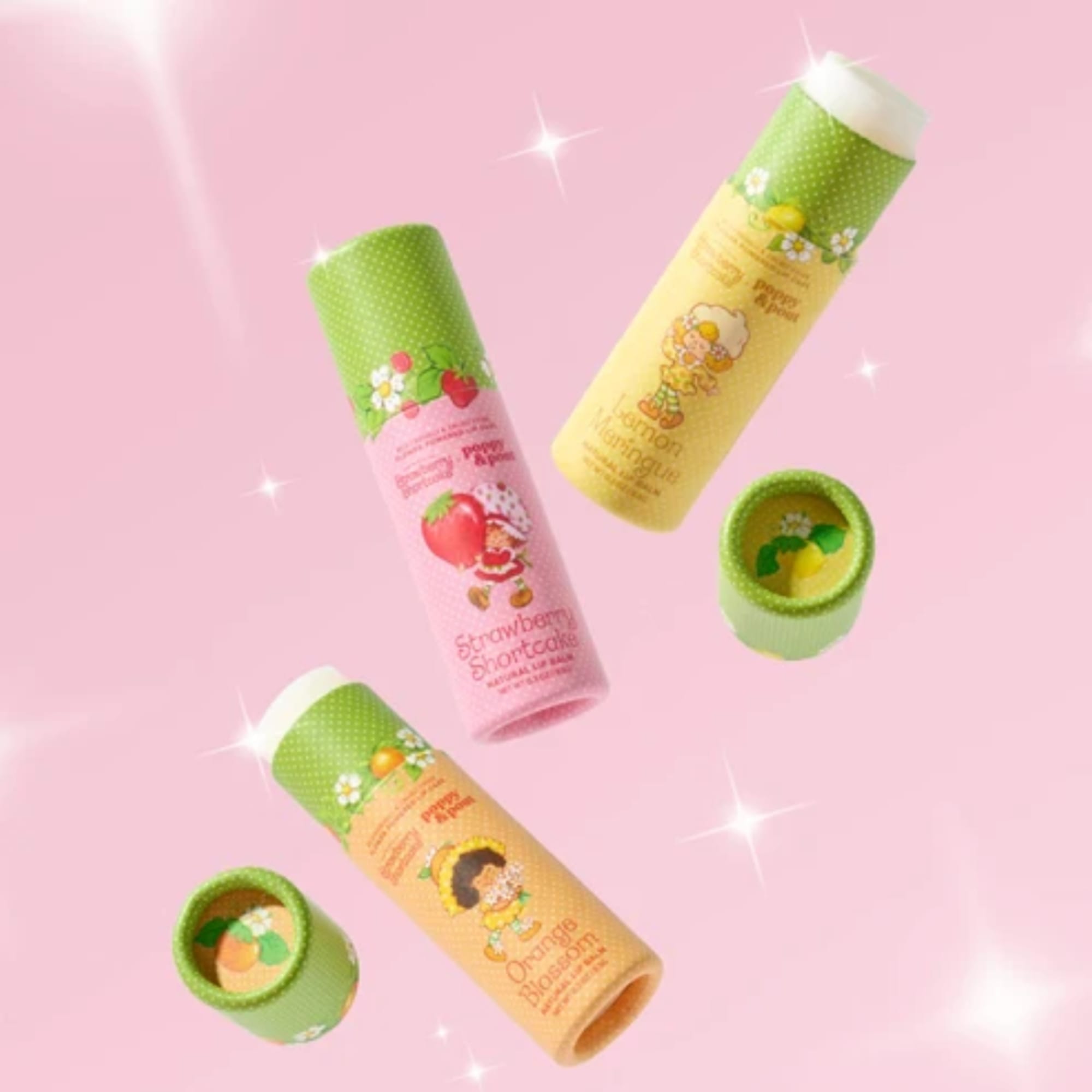 Four colorful cylindrical lip balm tubes on a pink background