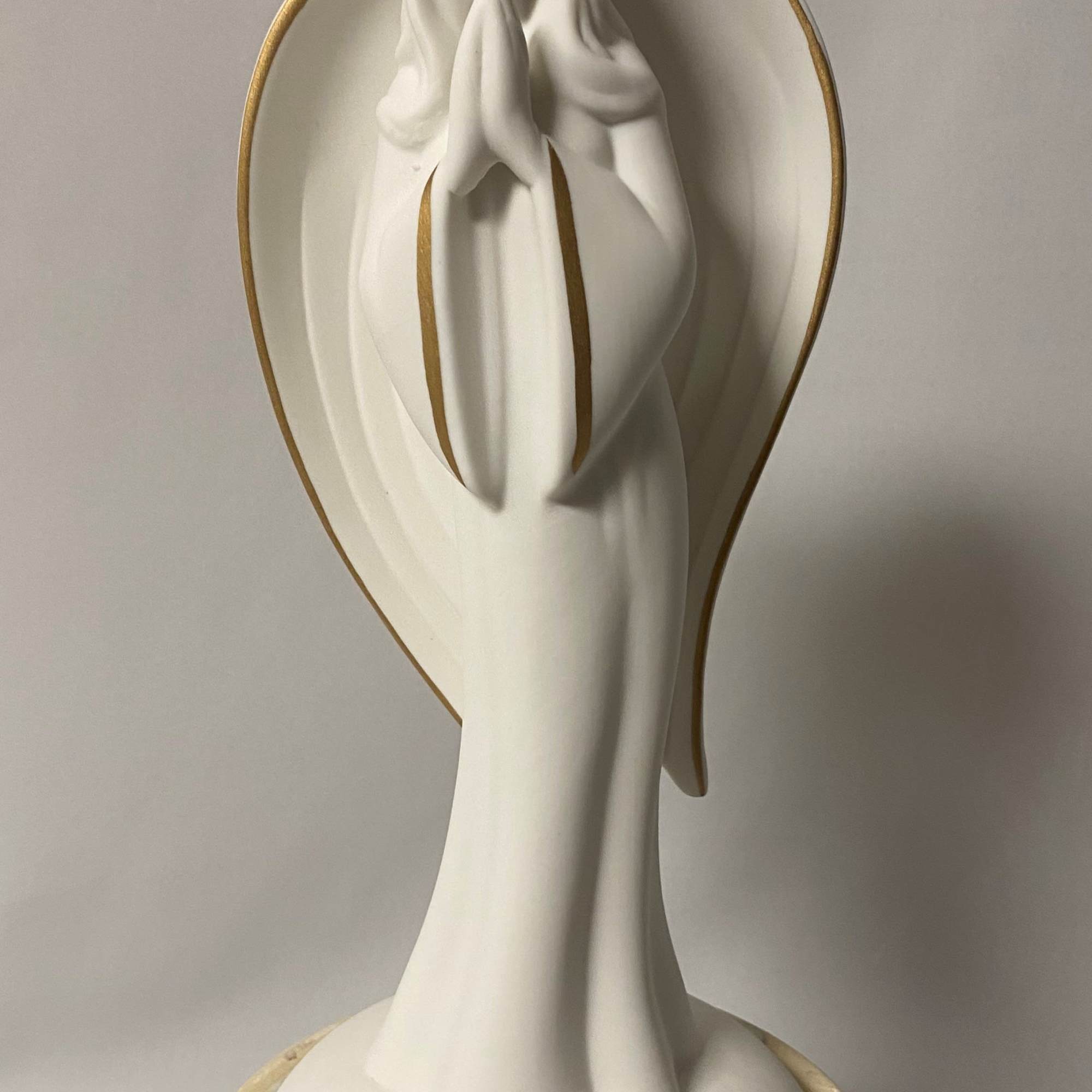 White praying angel statue with gold trim on a pedestal