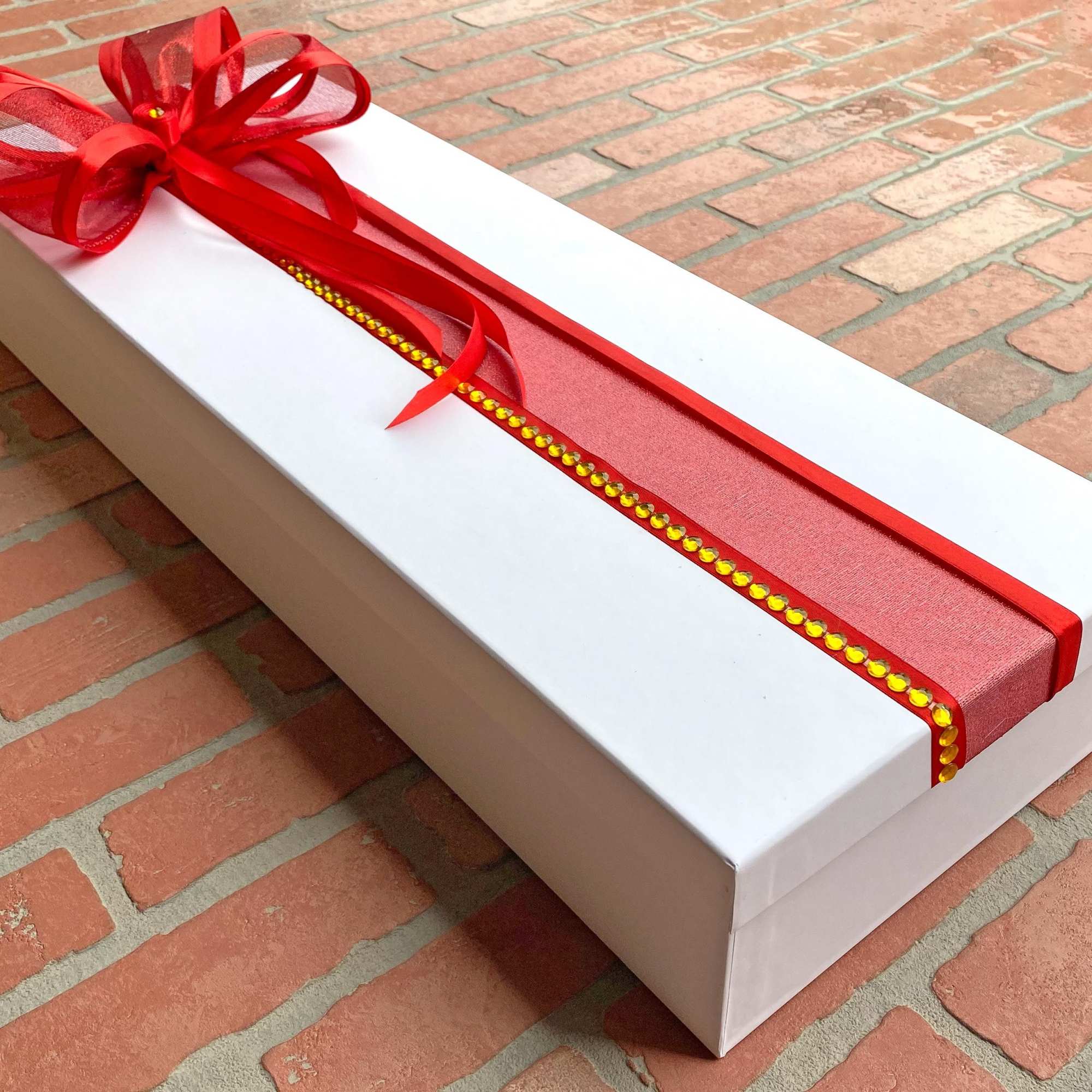 White rectangular gift box with a red ribbon bow on top