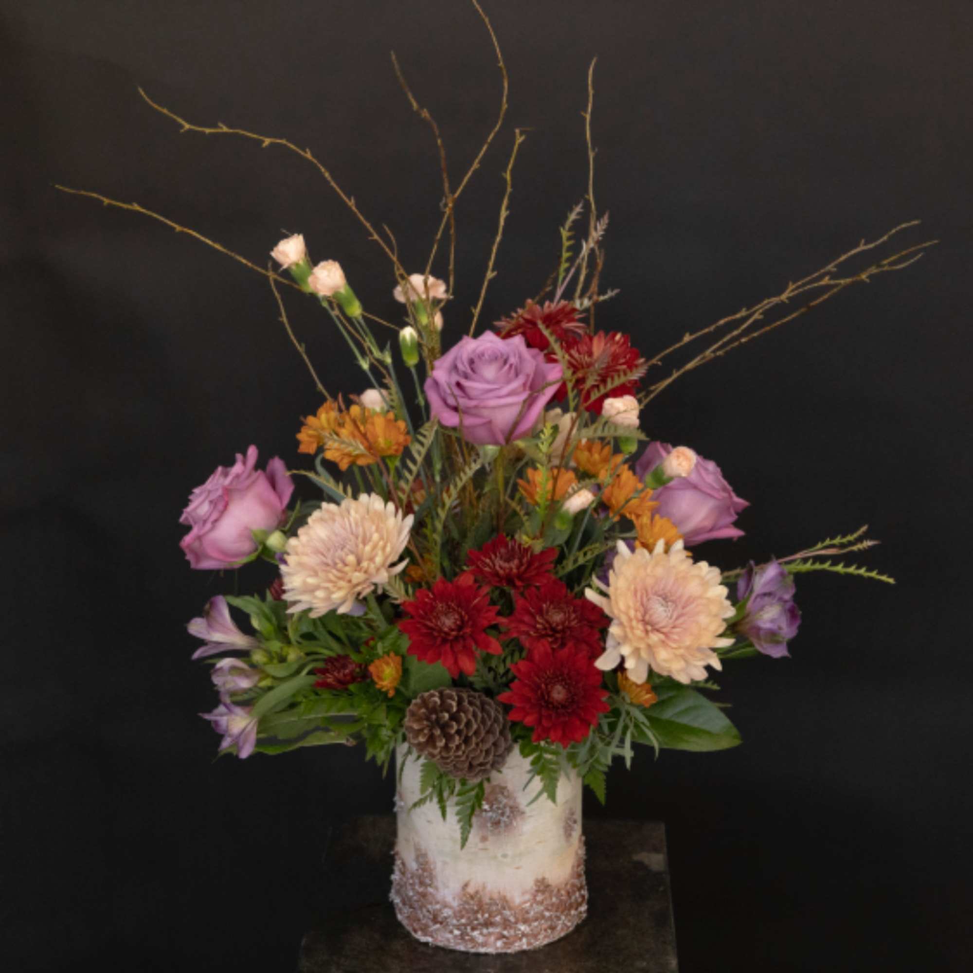 Mixed bouquet in a frosted vase with purple roses and red chrysanthemums