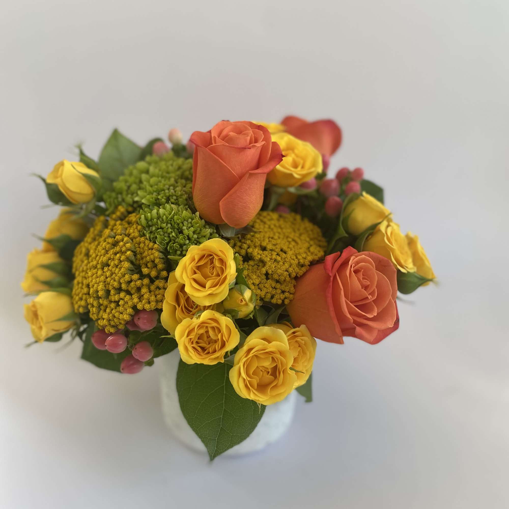 Compact bouquet of yellow and coral roses in a white vase