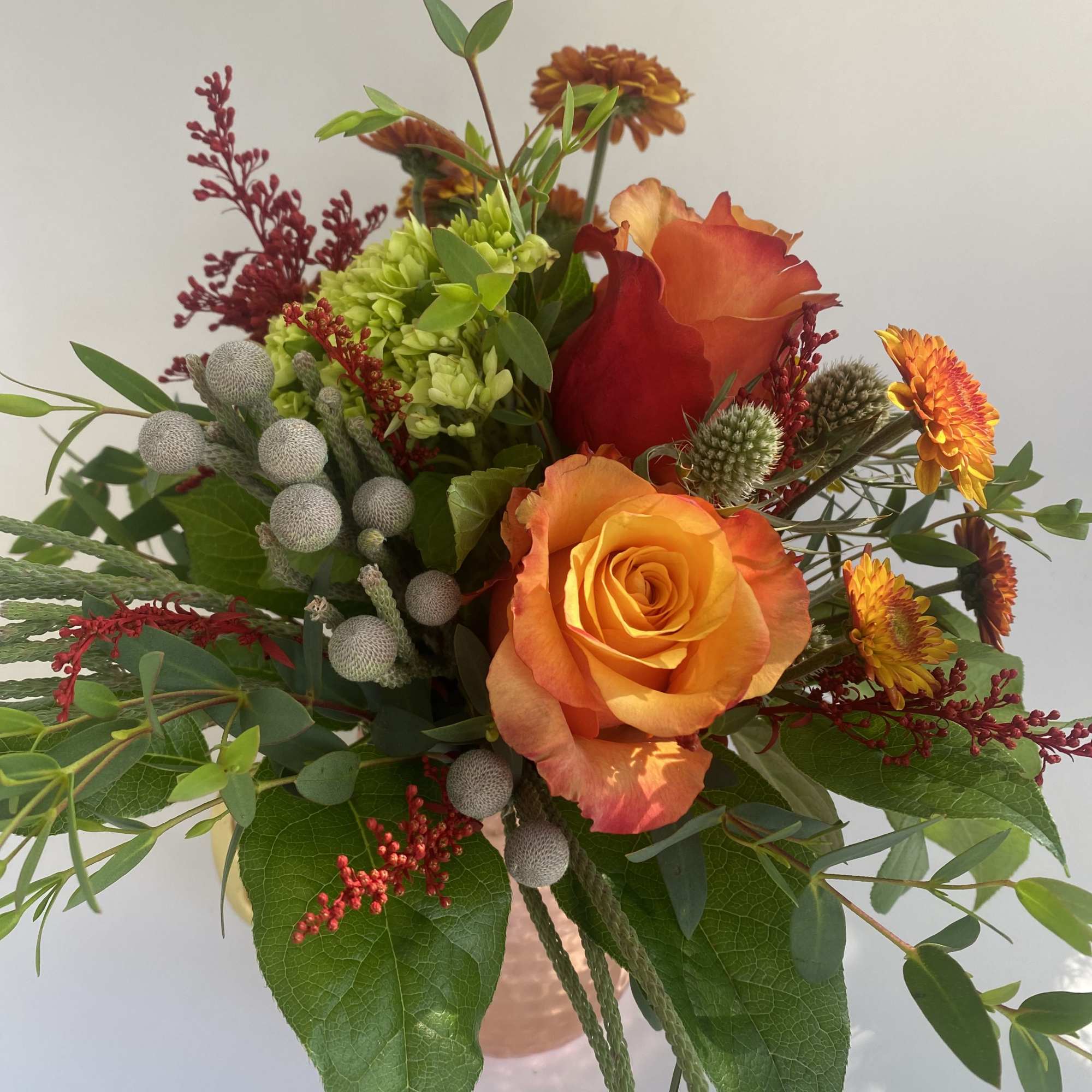 Orange roses and mixed flowers in a copper vase