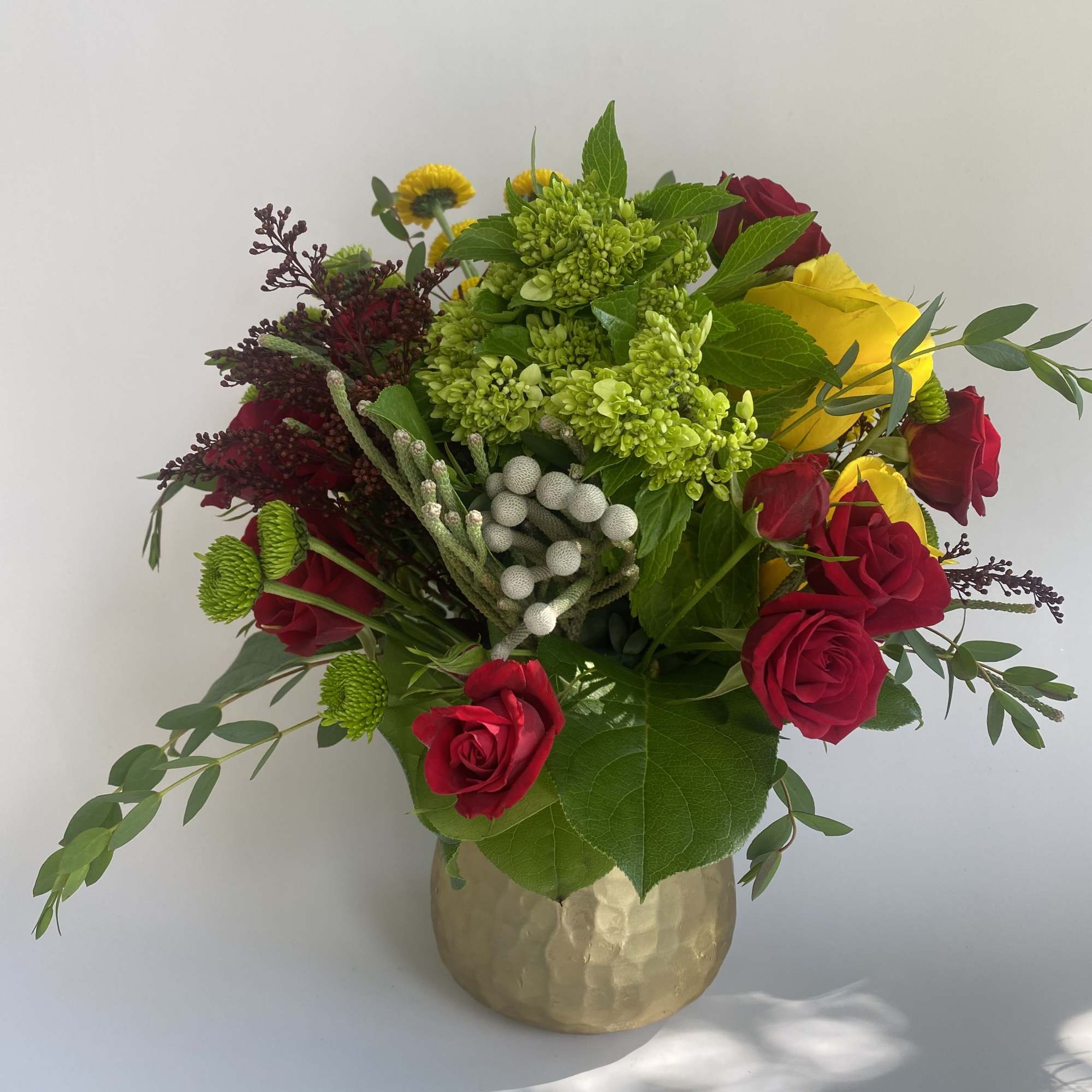 Bouquet of red and yellow roses in a gold vase