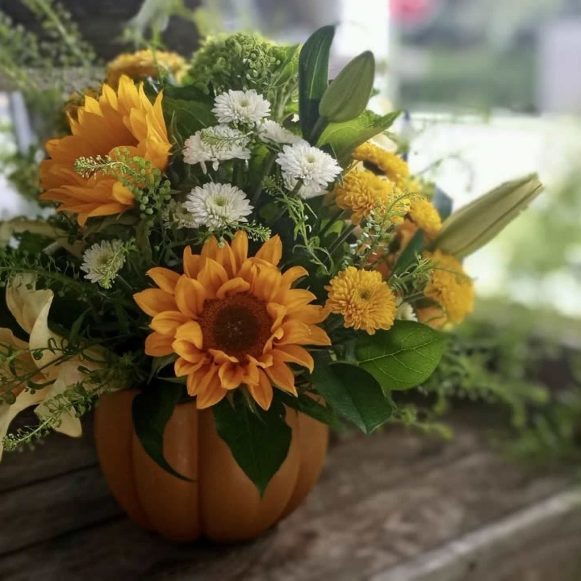 Orange and white floral arrangement in a pumpkin-shaped container