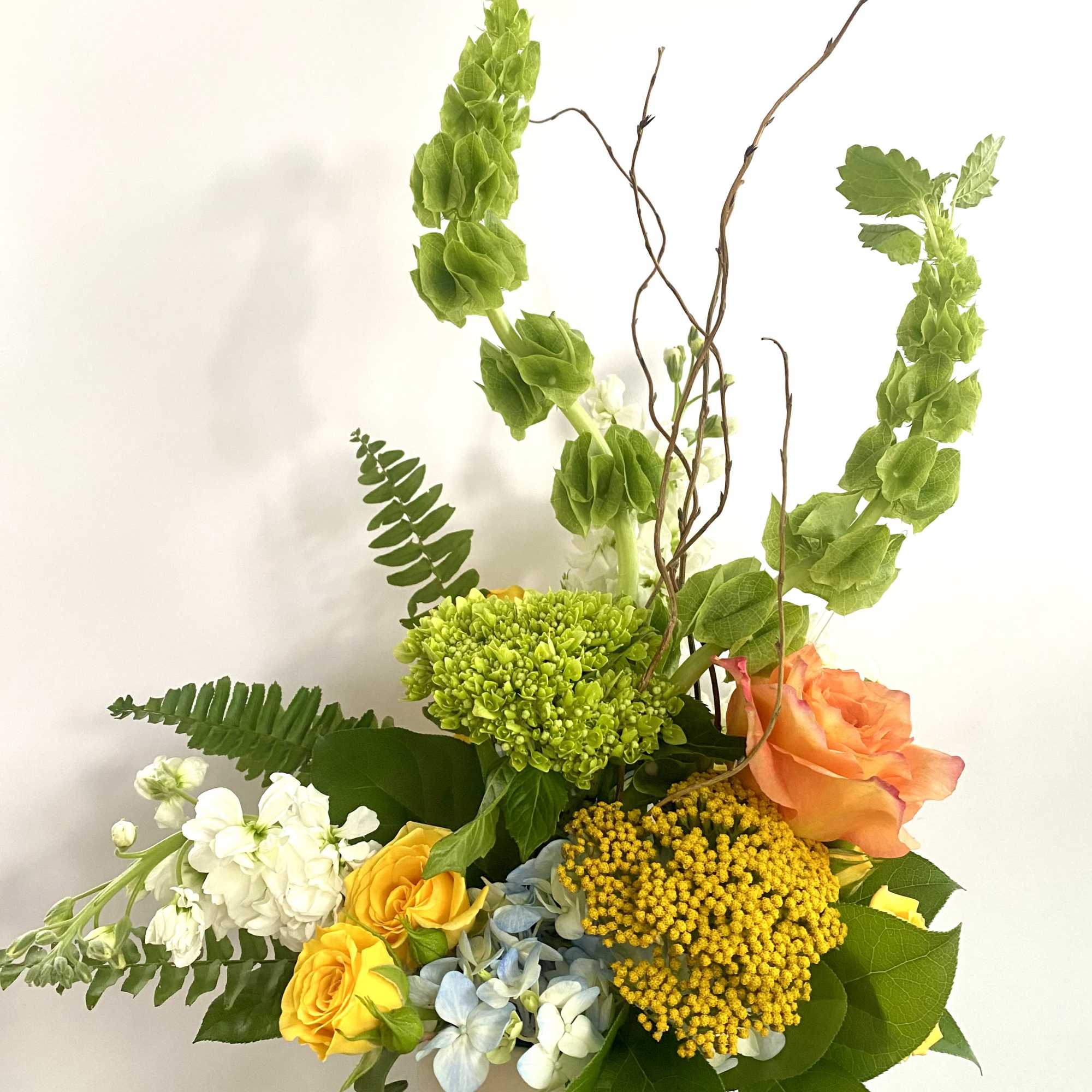 Mixed bouquet with orange and yellow roses in a white vase