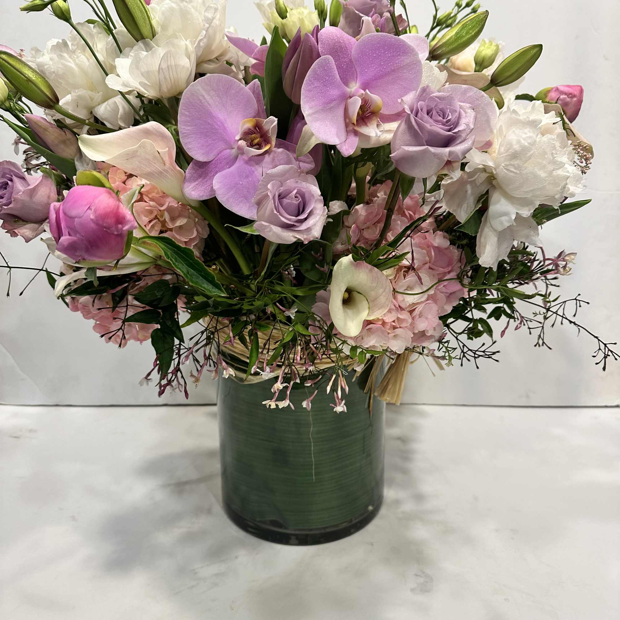 Medium high floral arrangement compose of an assortment of Jules Elie peonies