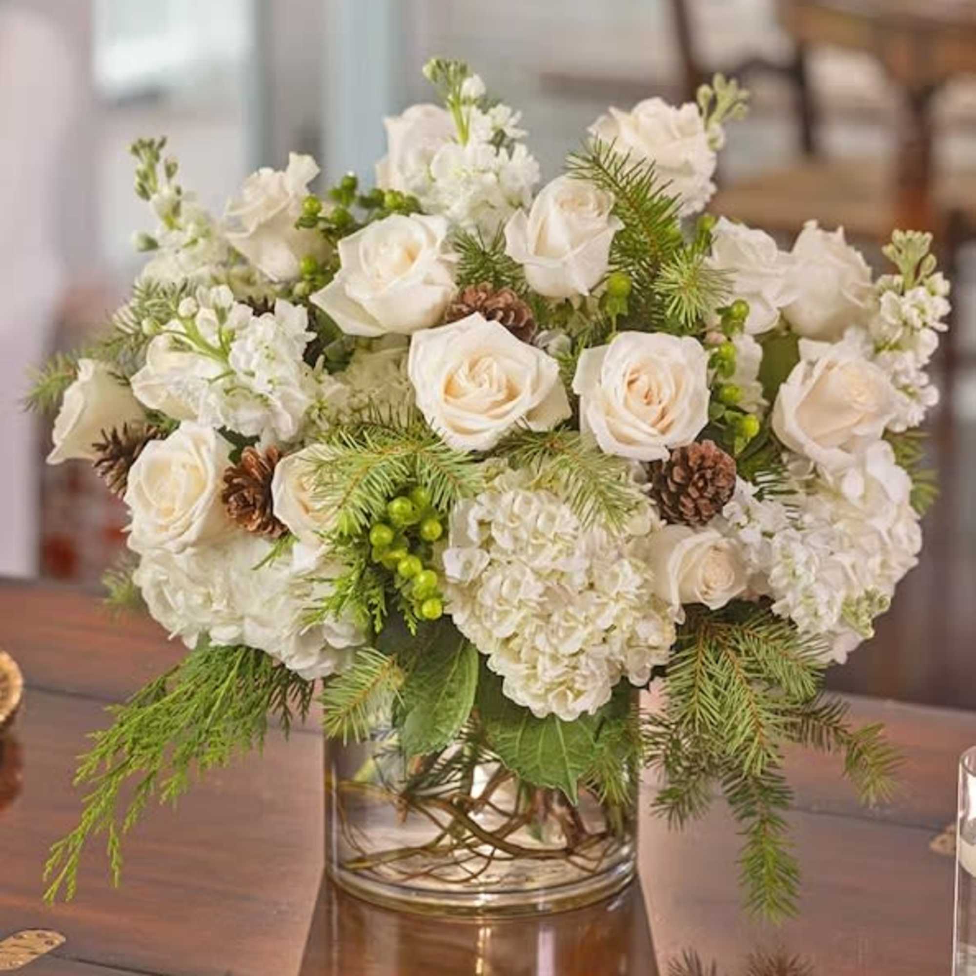 White roses and stock and scented winter cedars nestled in a snowy