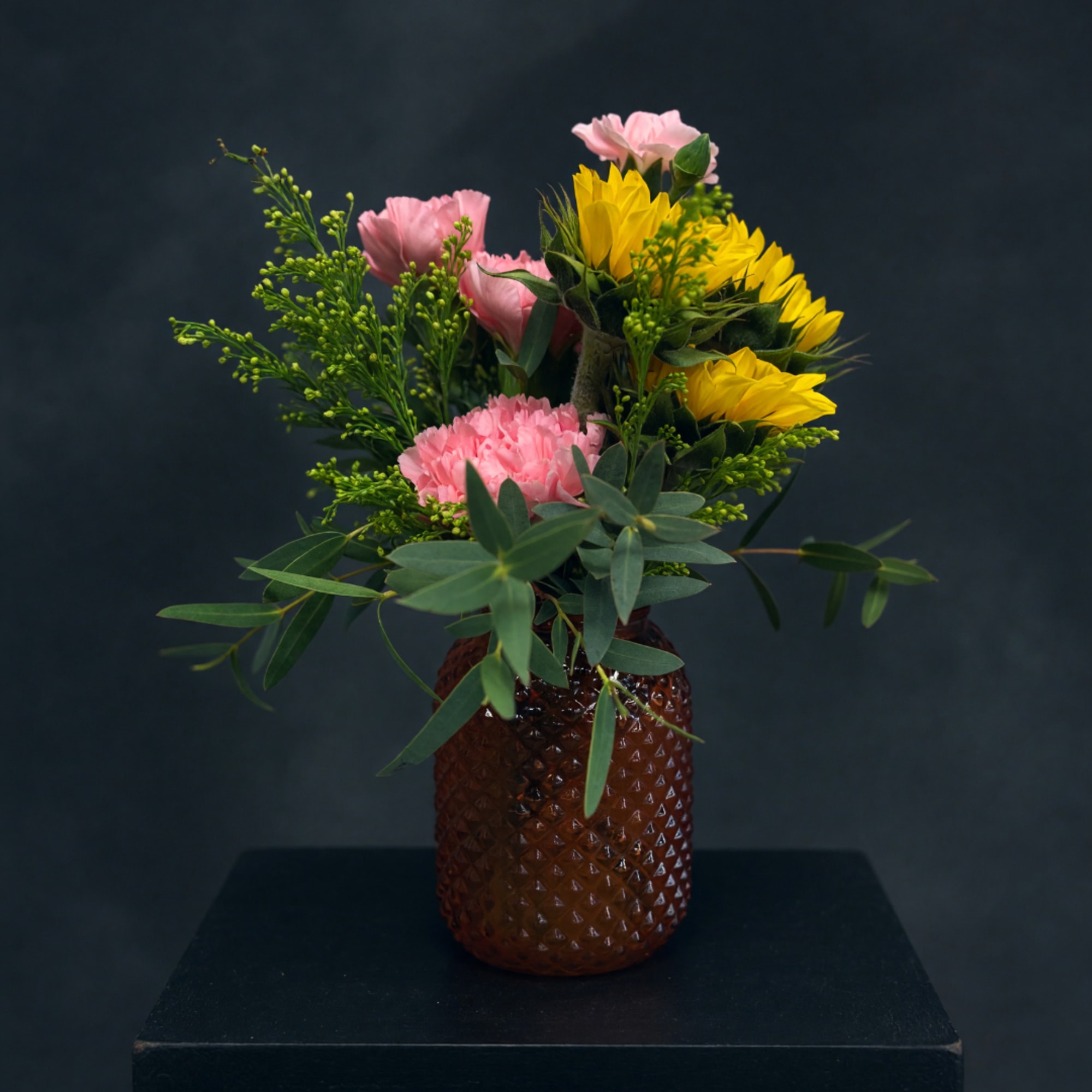 Pink and yellow flowers arranged in a brown textured vase