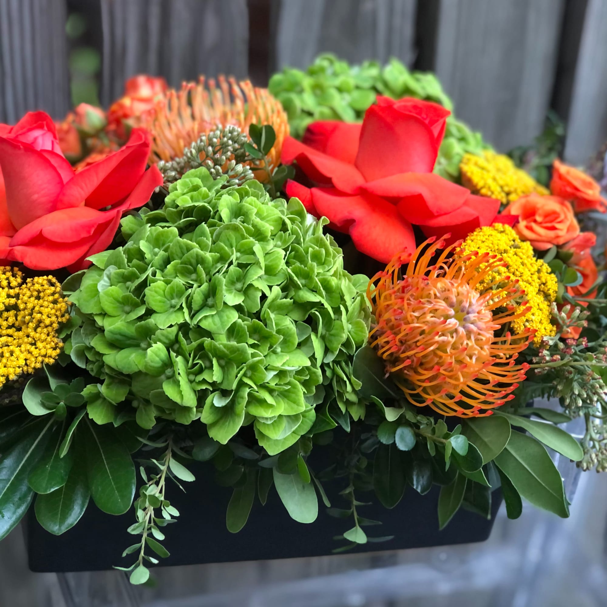Bright red roses and green hydrangeas in a low rectangular arrangement
